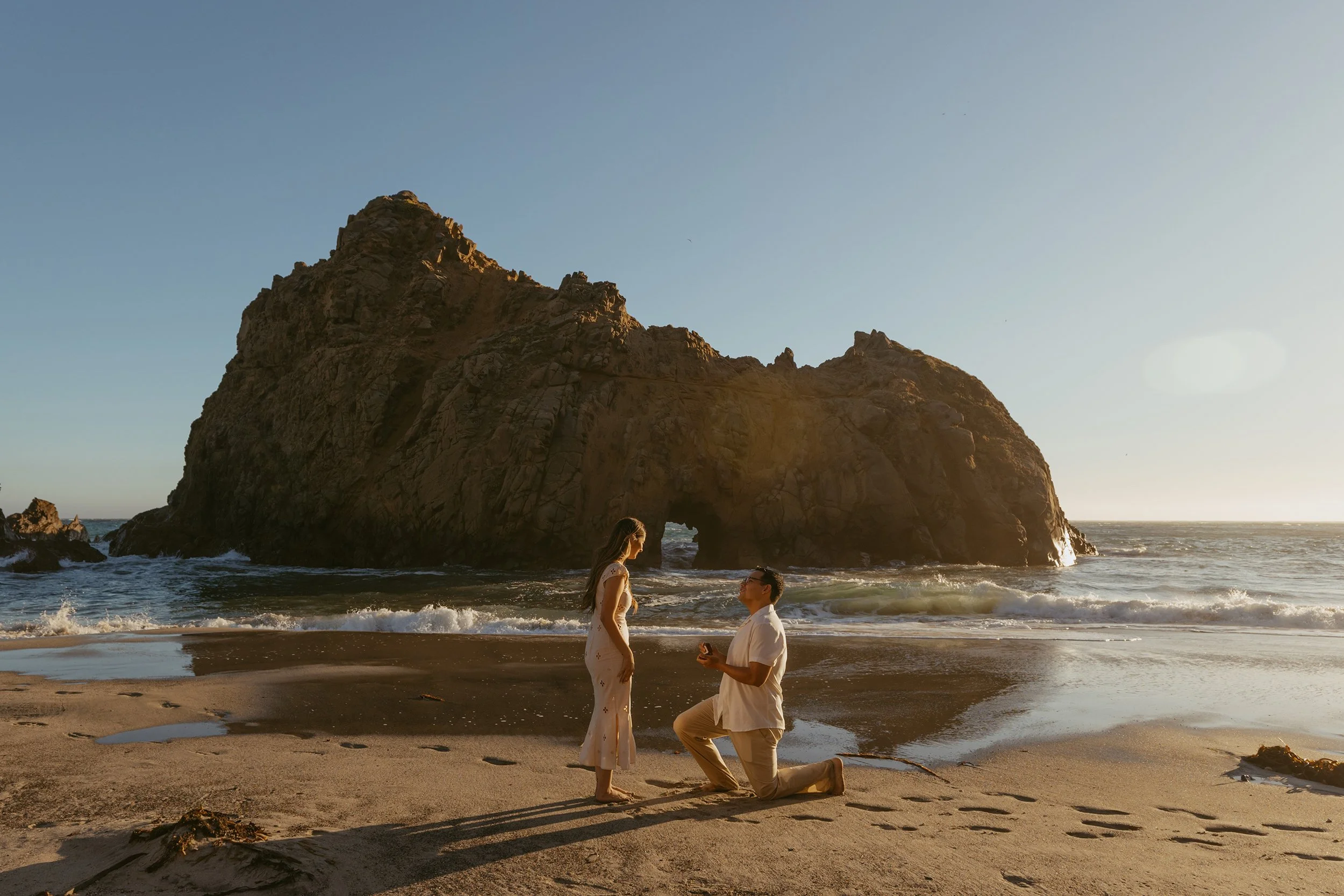 man proposing to woman in front of the Keyhole Arch on Pfeiffer Beach in Big Sur California