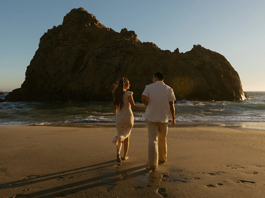 woman and man running towards the Keyhole Arch after getting engaged on Pfeiffer Beach in Big Sur California