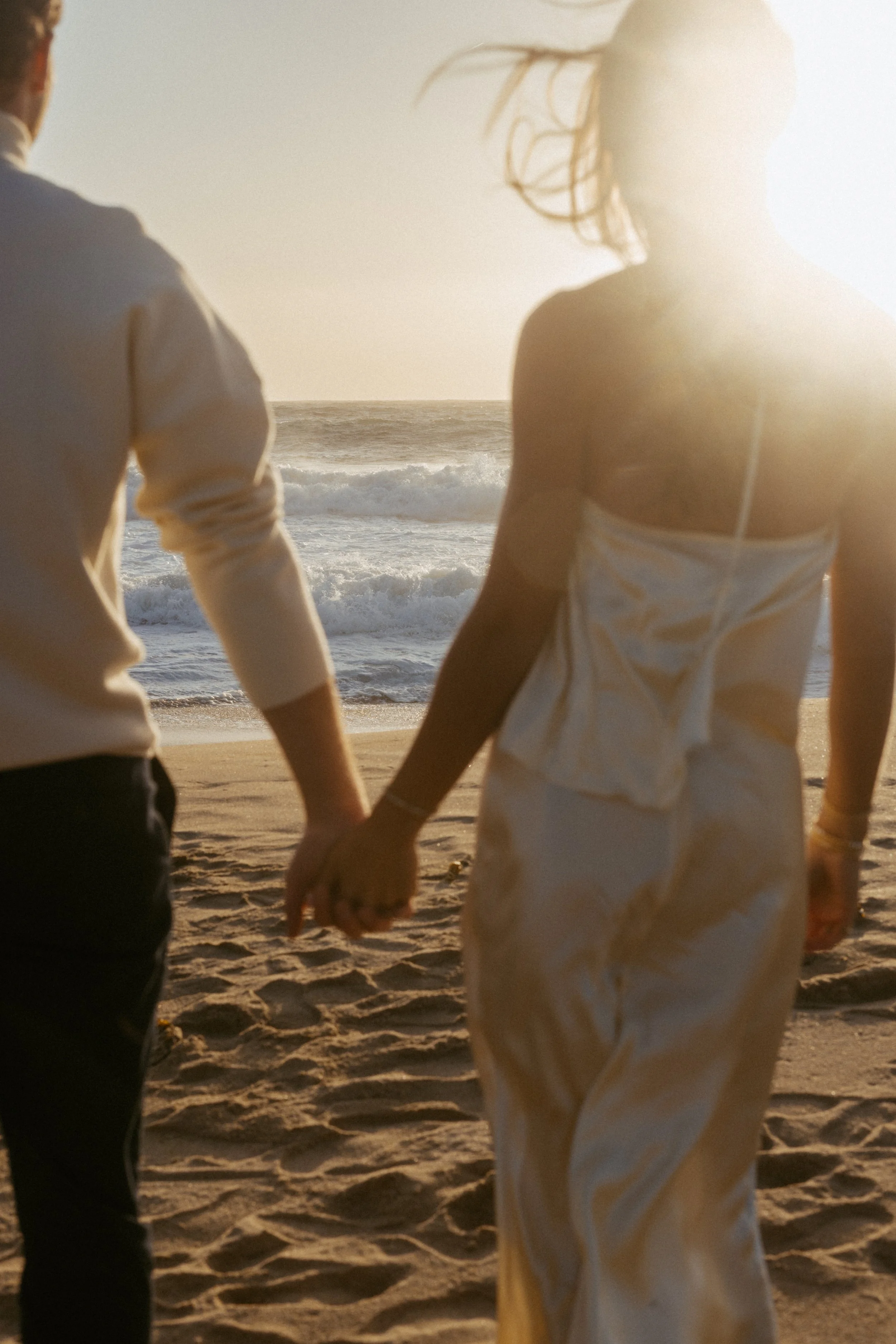 engaged couple holding hands looking at ocean during their engagement couples session in big sur