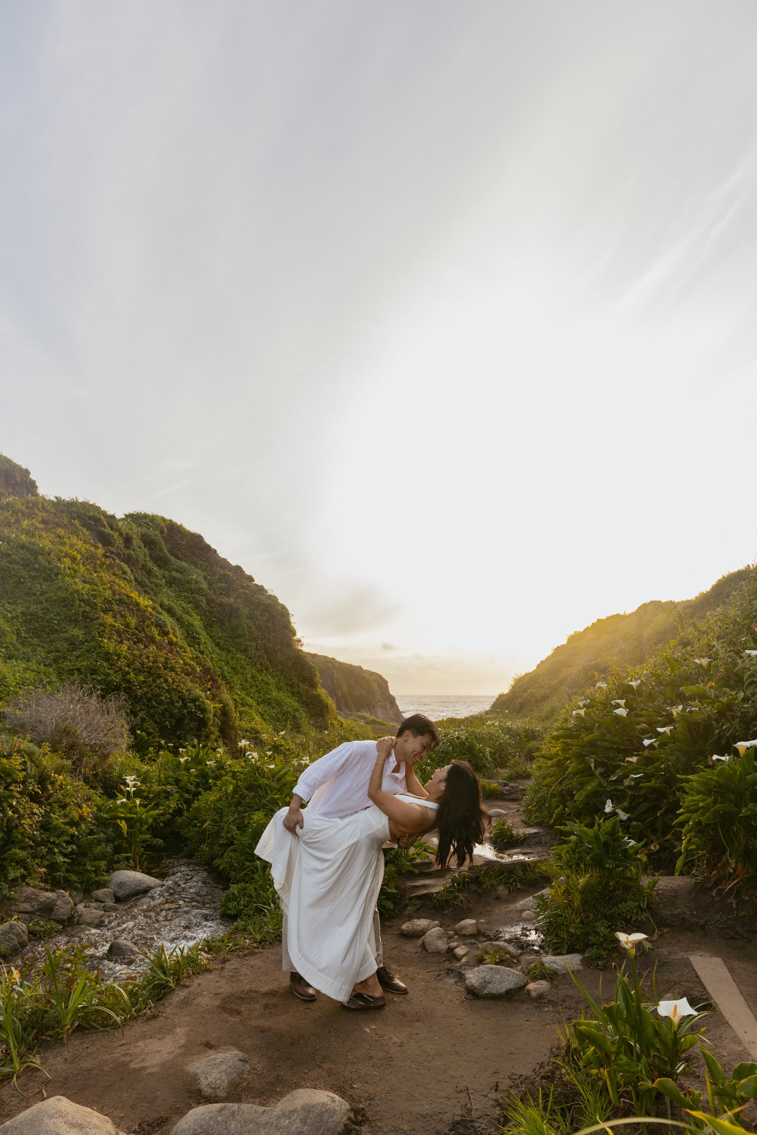 man dipping his girlfriend after proposing to her in big sur calla lily valley
