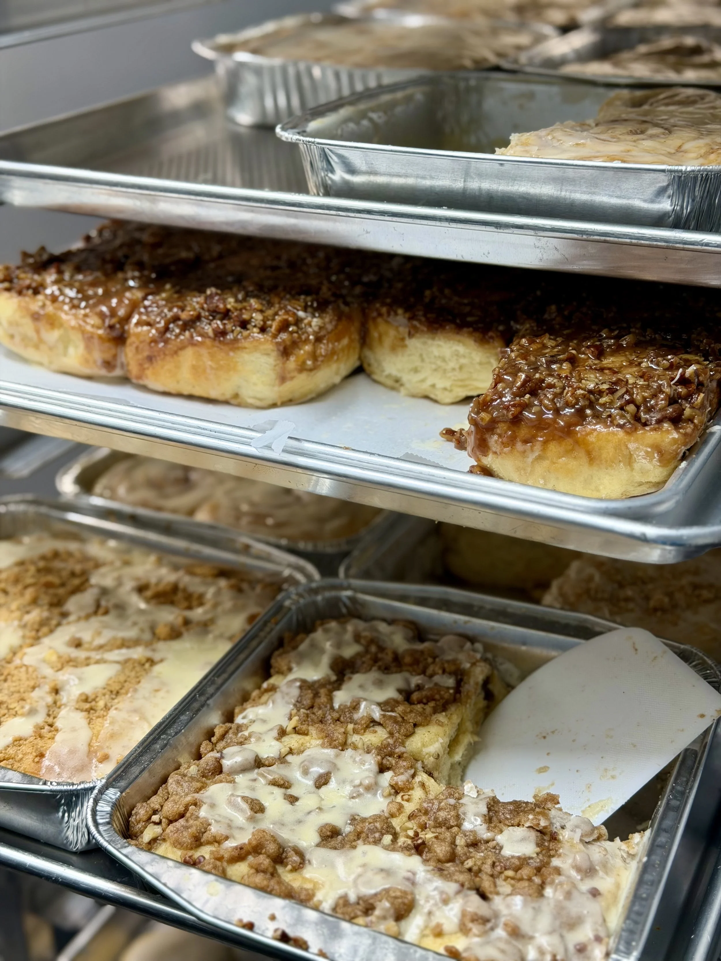 Assorted cinnamon rolls and bakery specials on trays at Salty Blonde Bakery in Hyde Park, Austin