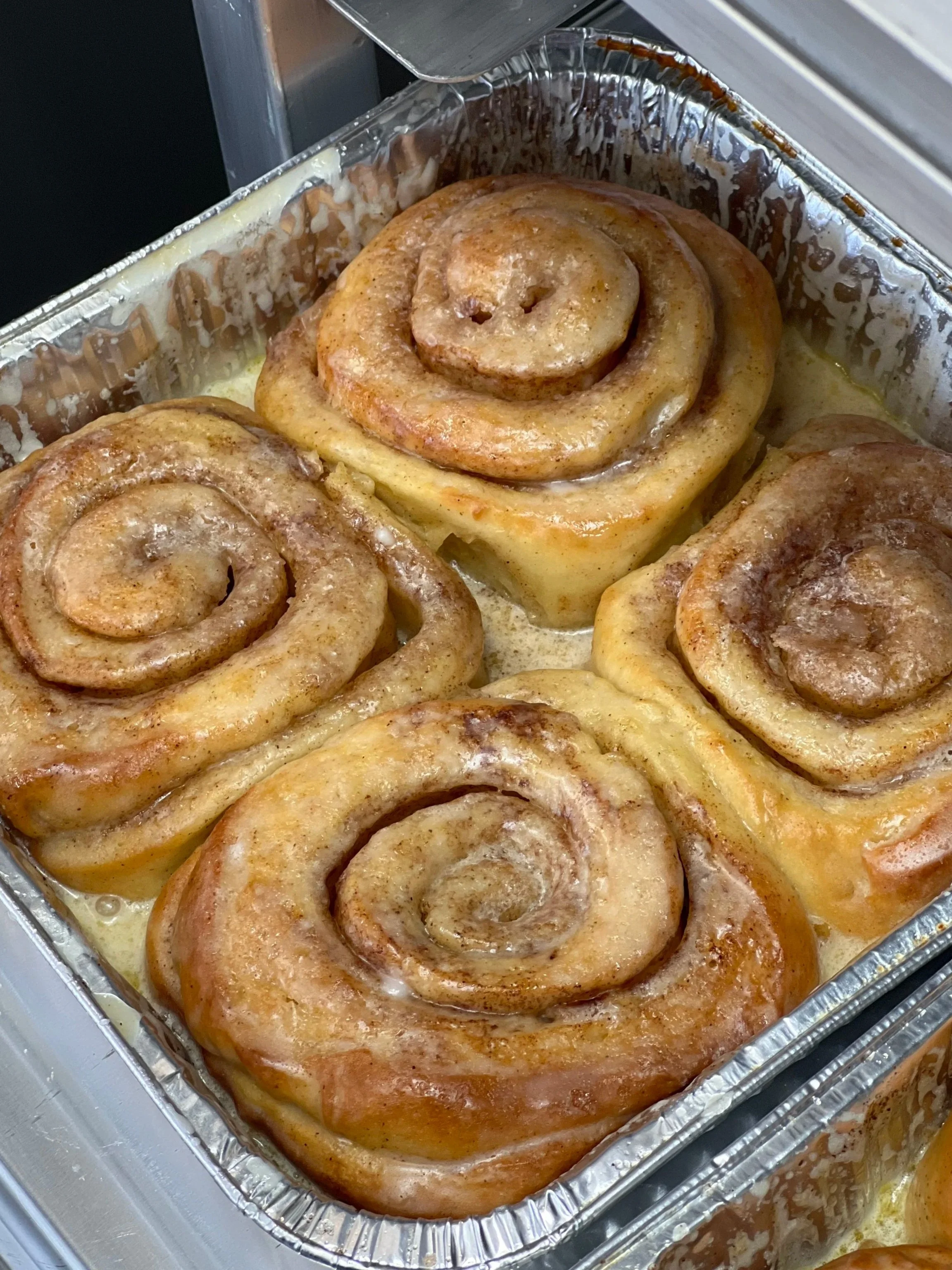 Four cinnamon rolls in a baking pan with icing.