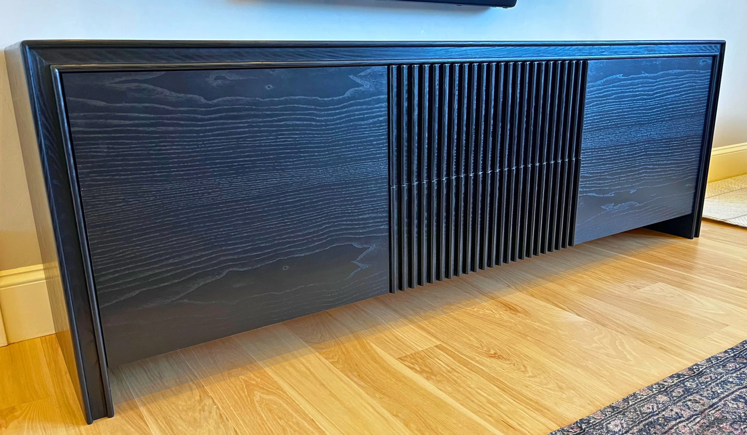 Modern black-stained ash media console with slatted doors, soft-close push-to-open drawers, and a hand-rubbed natural durable finish, custom built in Midway, Utah.
