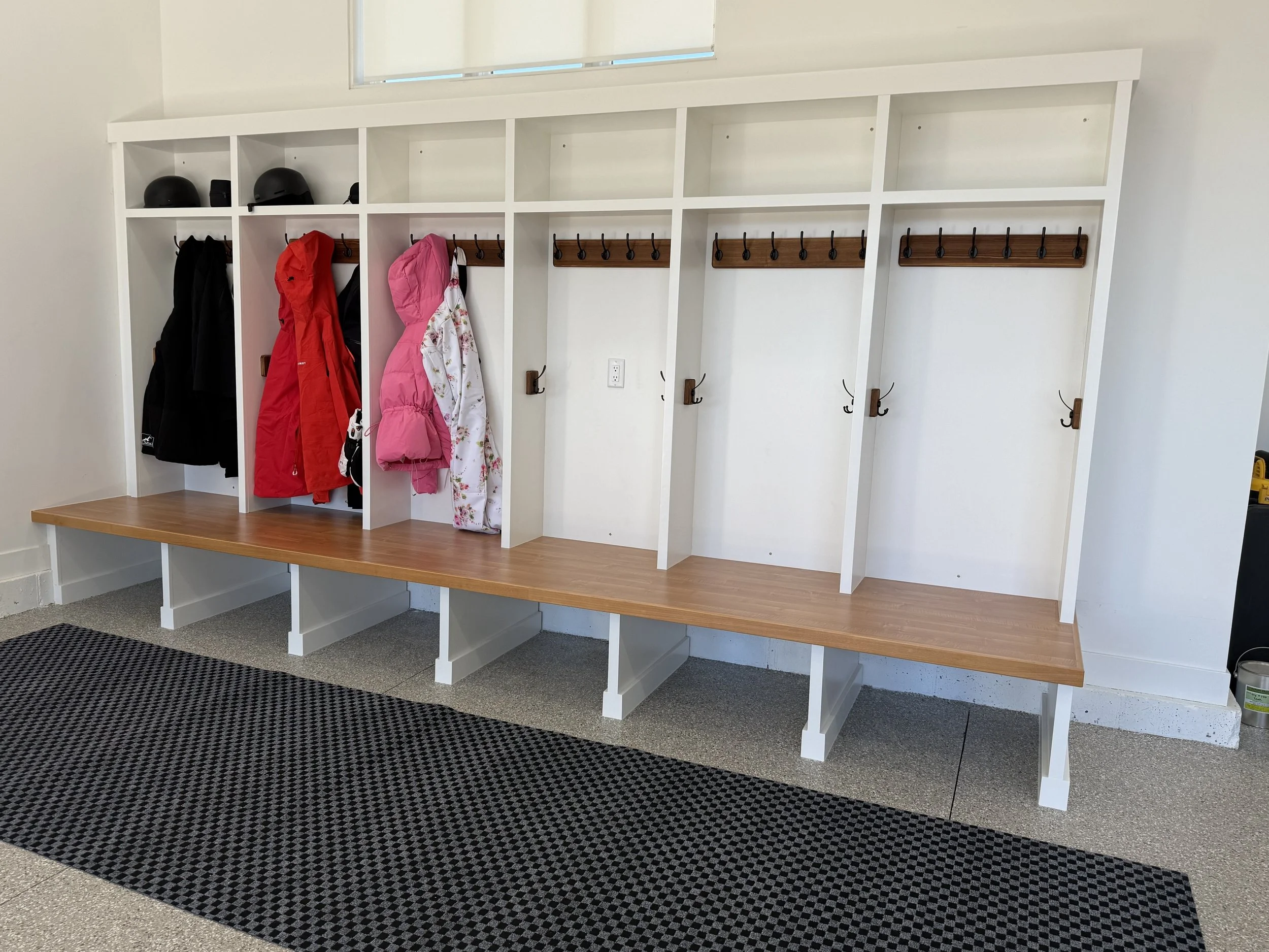 Custom-designed mudroom ski lockers with oak bench seating, metal hooks, and integrated winter gear storage, built in Midway and installed at Red Ledges in Heber Valley, Utah.