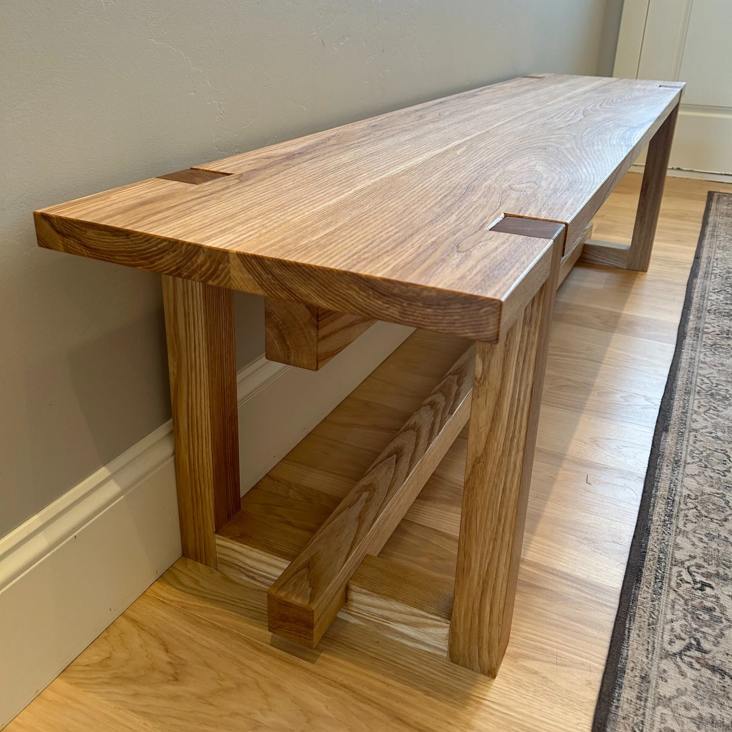 Bespoke 7-foot entryway bench in a Japanese-inspired design, built from solid ash hardwood with traditional exposed joinery and a durable, hand-rubbed all-natural finish in a Midway, Utah home