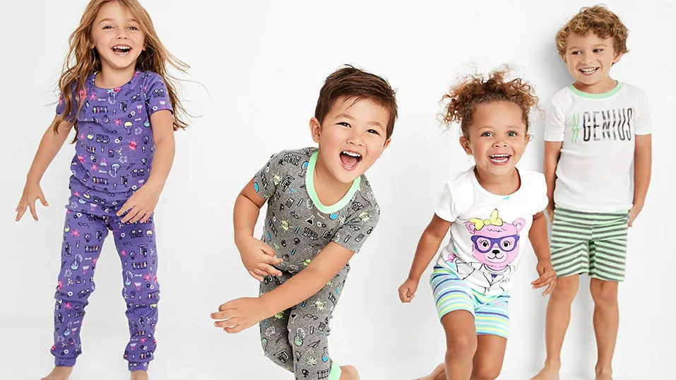 Four children wearing colorful pajamas, smiling and playing.