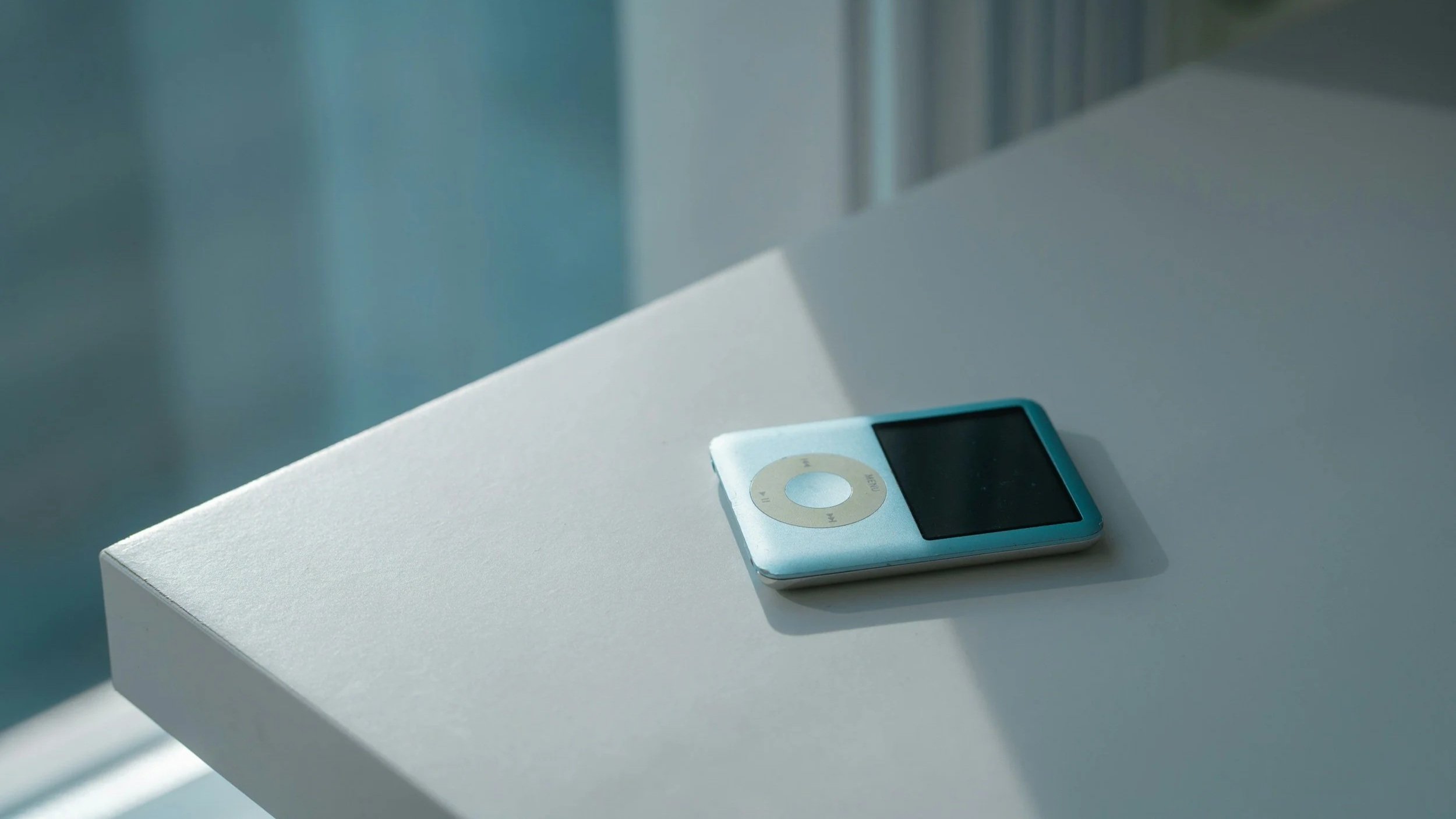 blue ipod classic on a white countertop with warm morning light coming through the window