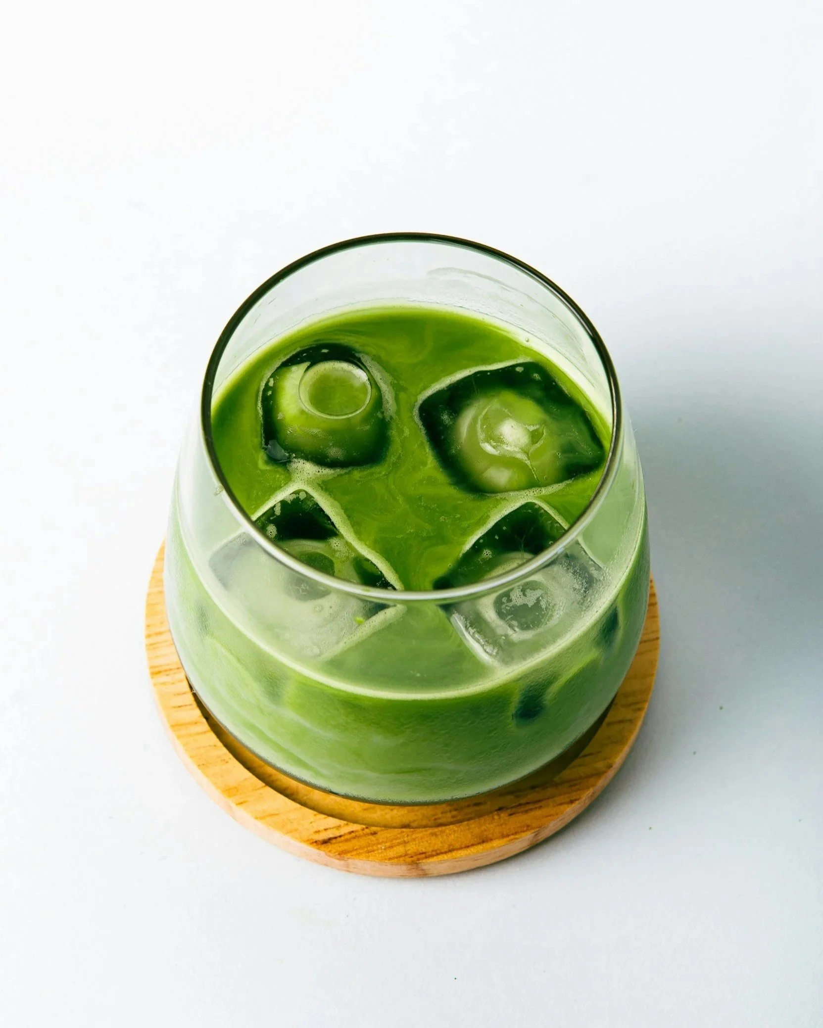 vibrant iced matcha latte on wooden coaster