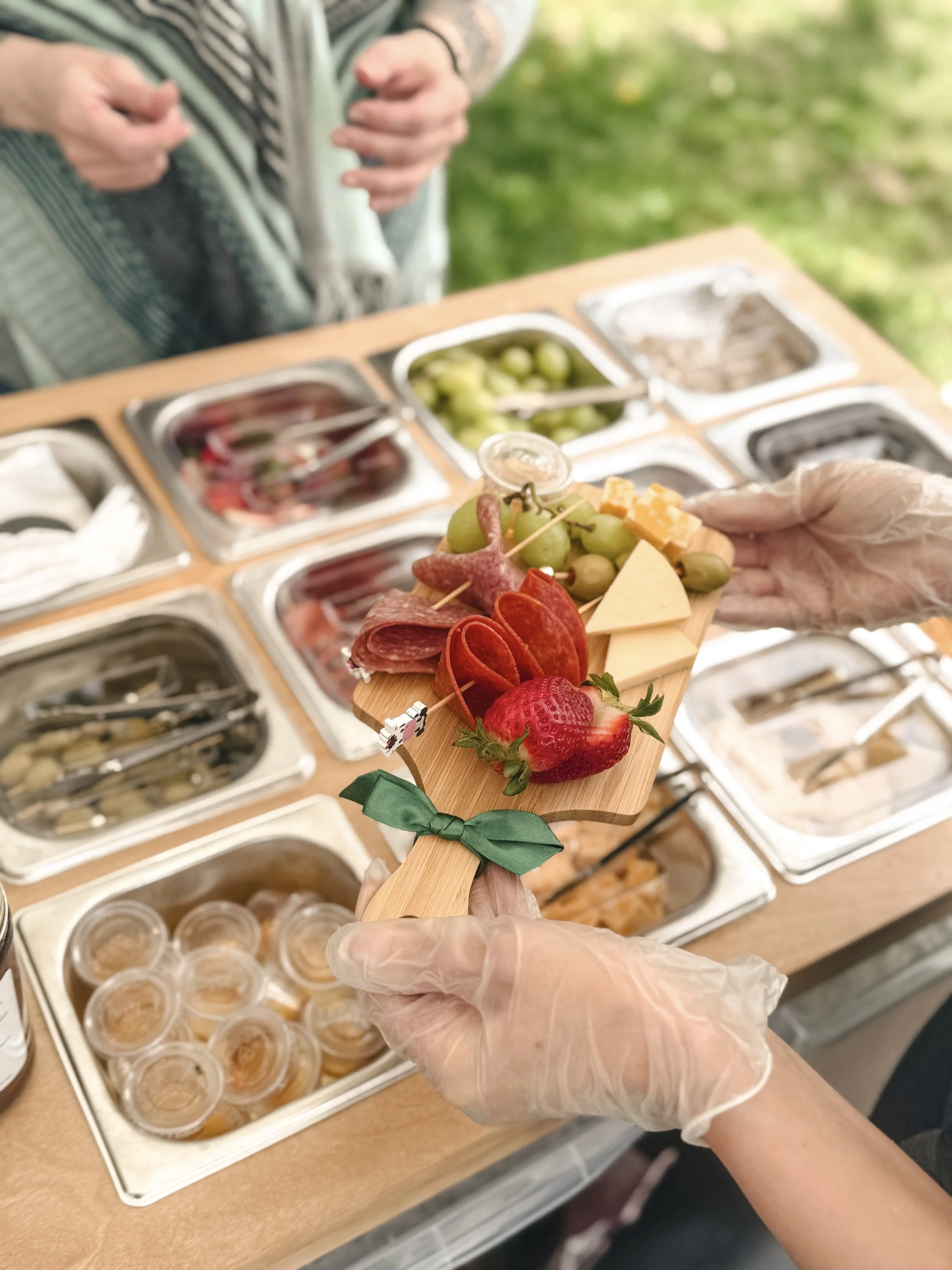 Charcuterie board being served with meats, cheeeses, fruits and accompaniments. Showing a fully stocked charcuterie cart.