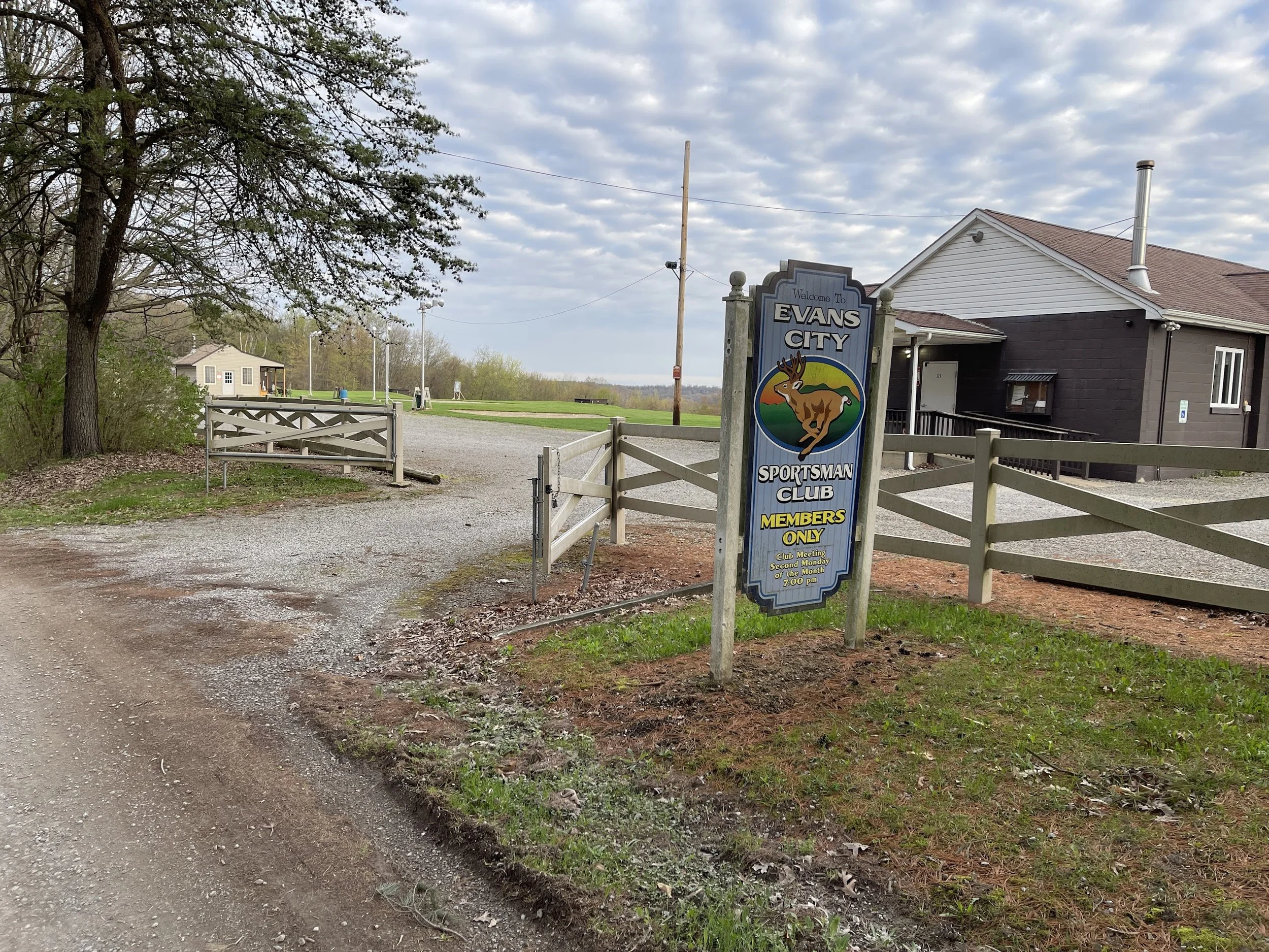 Sign at Evans City Sportsman Club indicating it is for members only, with a small building and trees in the background.