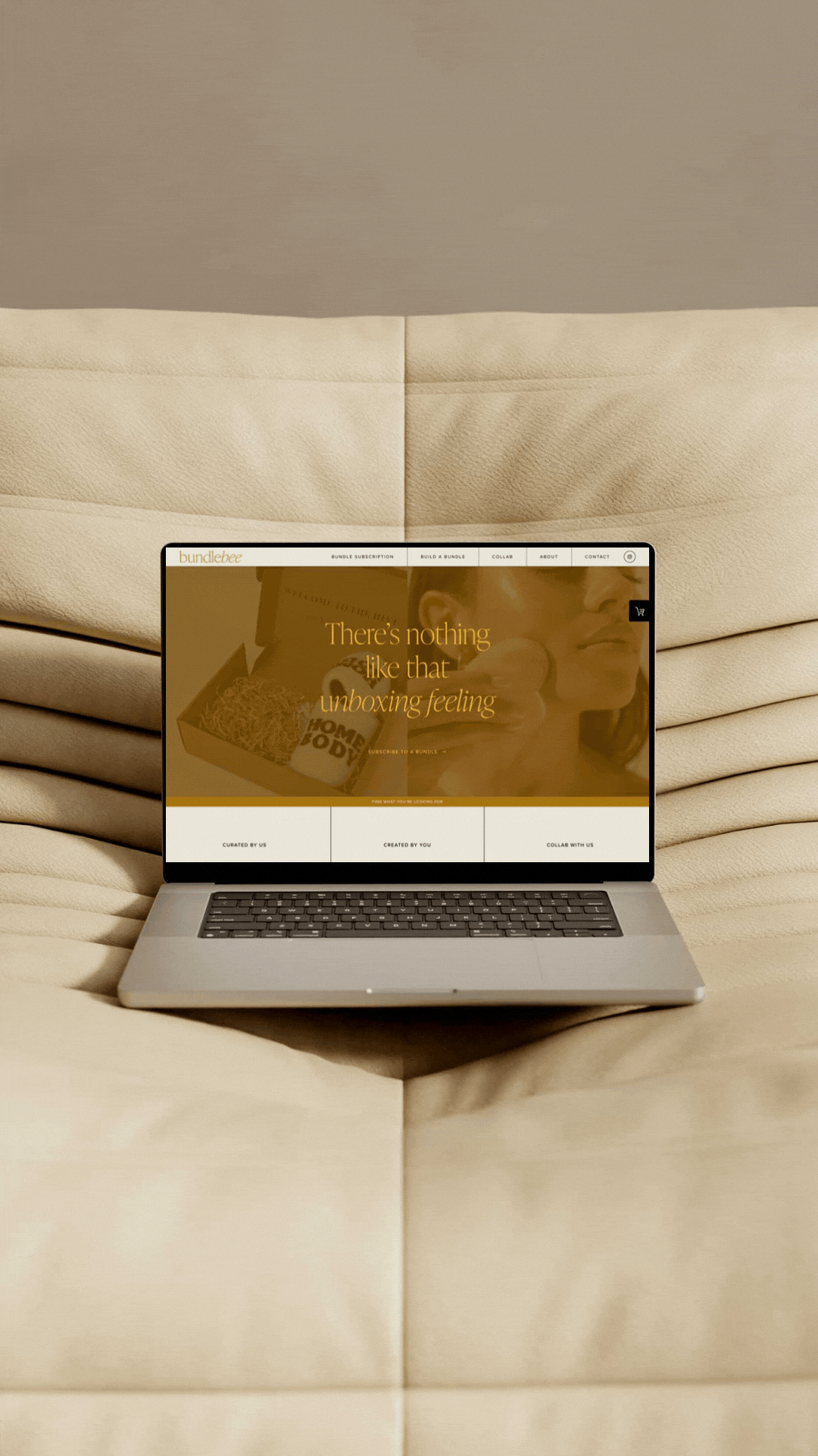 Laptop placed on a cream-colored textured fabric surface, displaying a website scrolling on the screen.