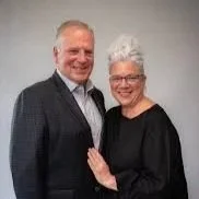 A man and woman standing together, smiling and posing for a photo.