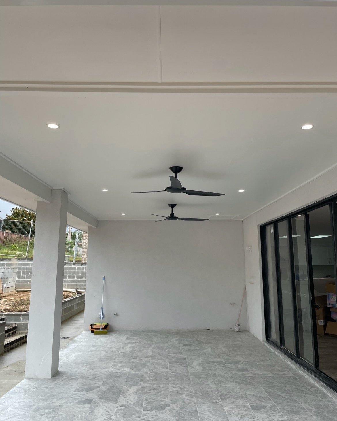 Covered outdoor patio with ceiling fans and tile flooring