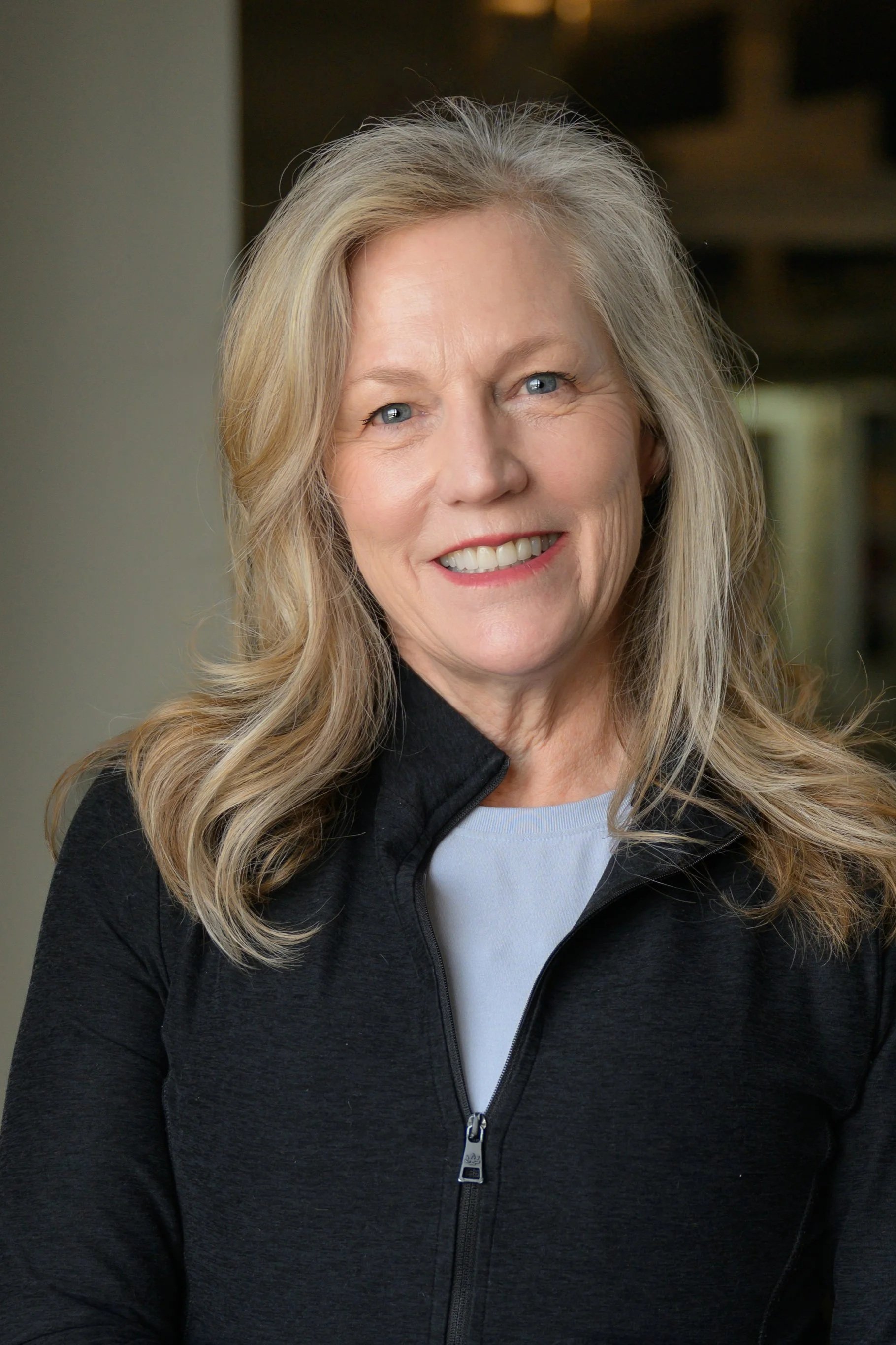Portrait of a woman with long hair, wearing a dark jacket, smiling in black and white.