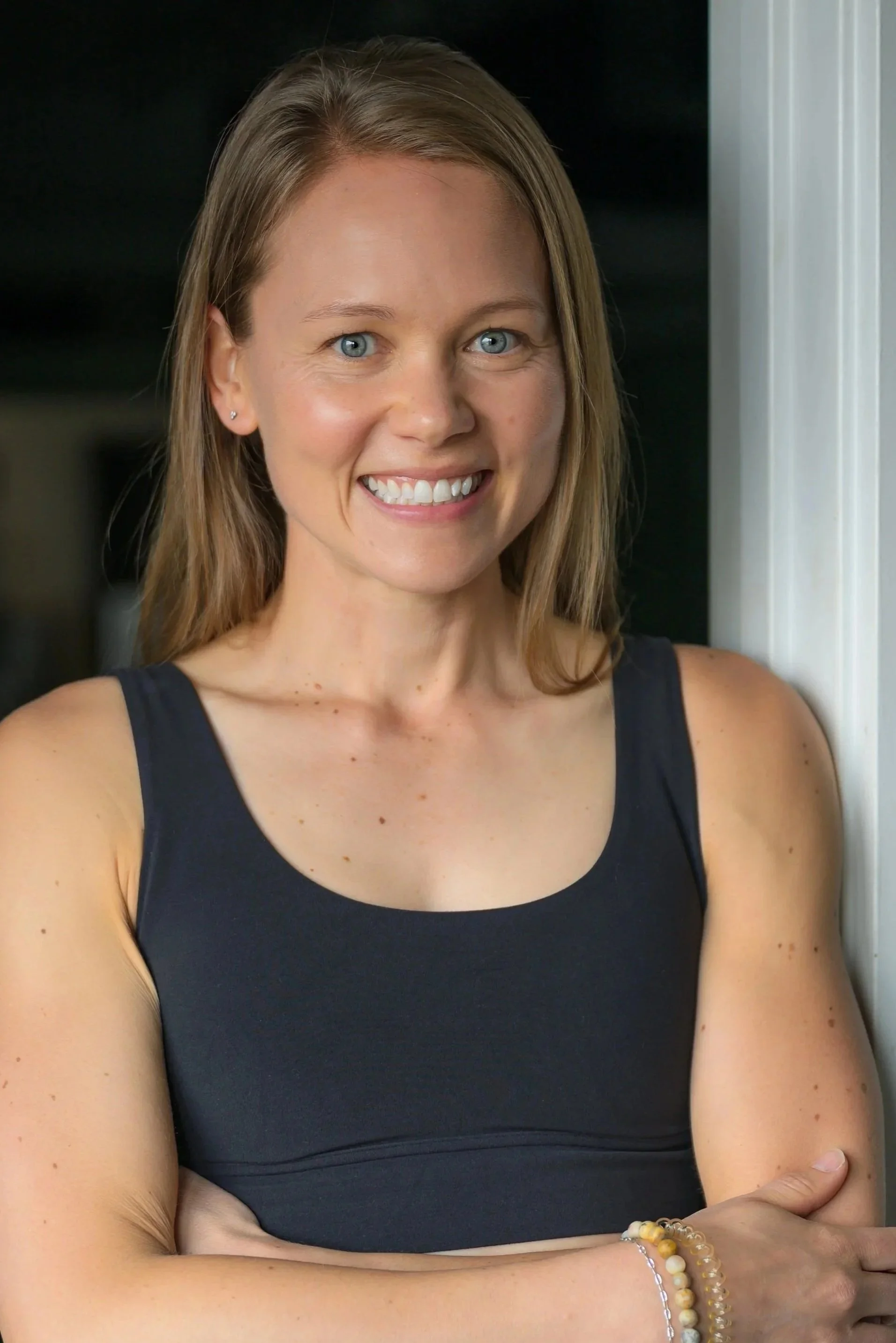 Black and white portrait of a smiling woman with long hair wearing a sleeveless top.