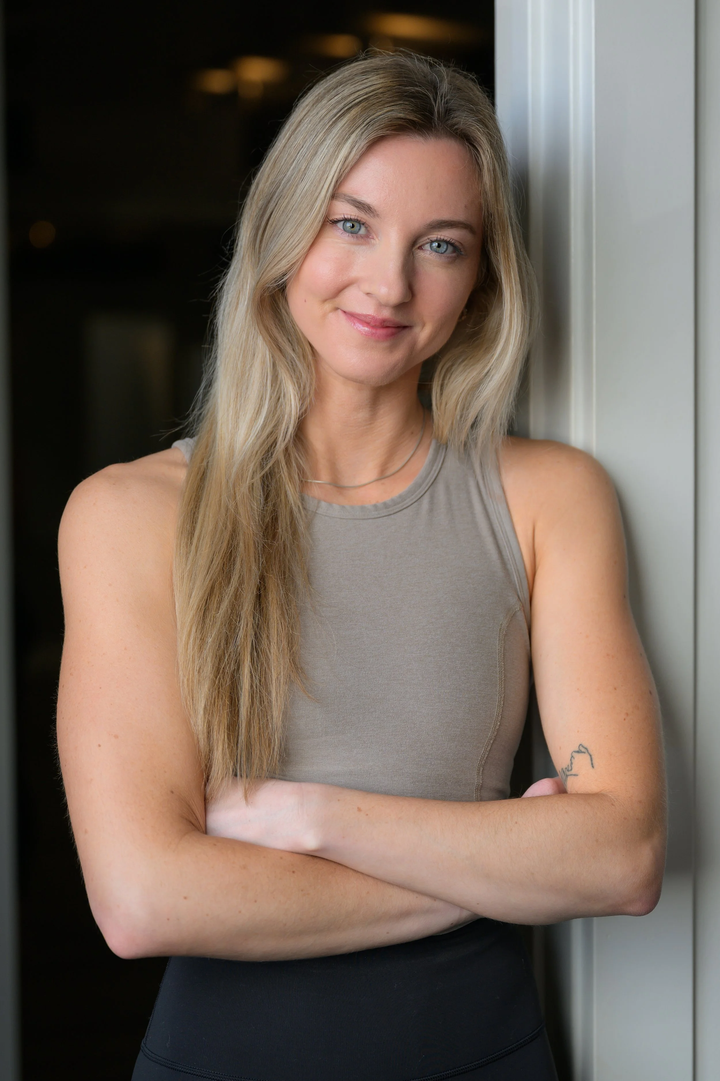 Black and white photo of a smiling person with long wavy hair wearing a tank top.