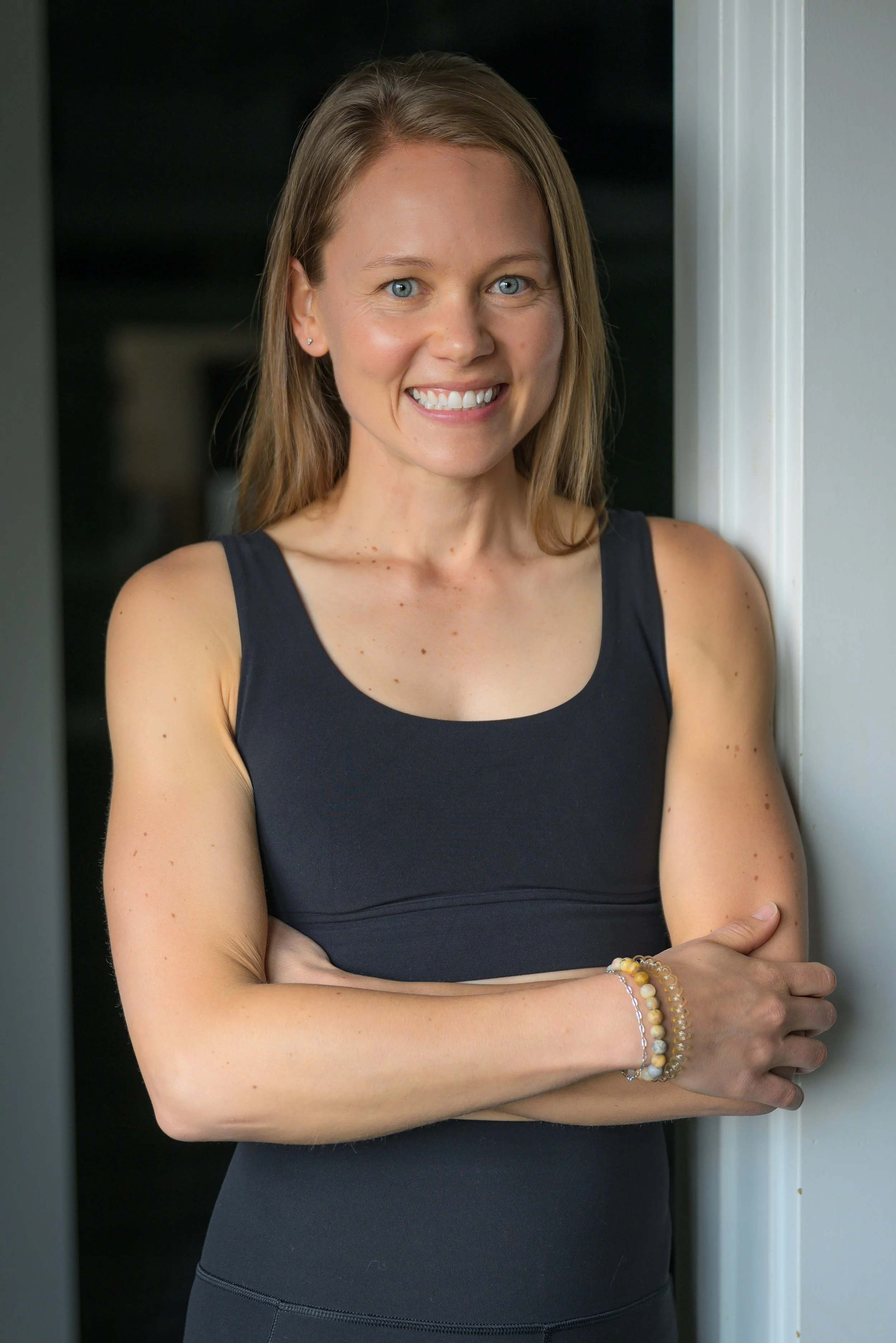Black and white portrait of a smiling woman with long hair wearing a sleeveless top.