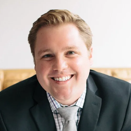 Close-up portrait of a smiling young man in a suit and tie.