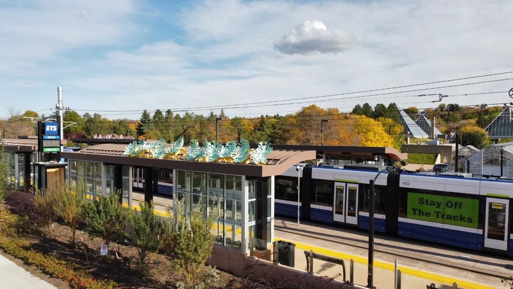A train at a street-level Valley Line Southeast stop beside a Stay Off the Tracks safety sign