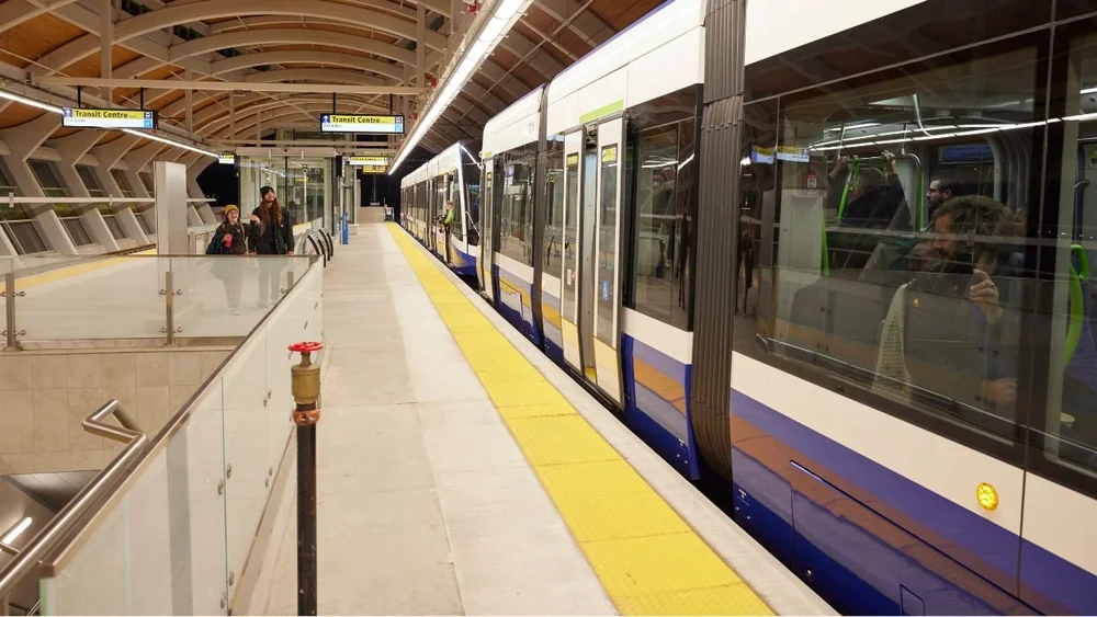 Passengers on a covered Valley Line Southeast platform as a train pulls in