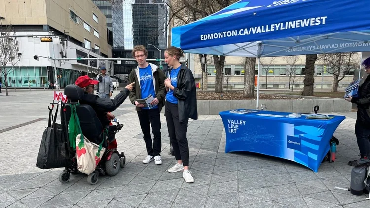 A team member talking with residents at the booth in front of the safety banner