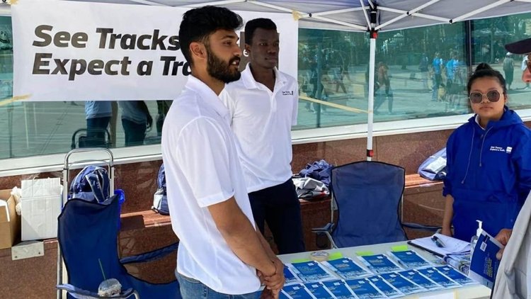 Street team tents with See Tracks Expect a Train banners on a downtown plaza