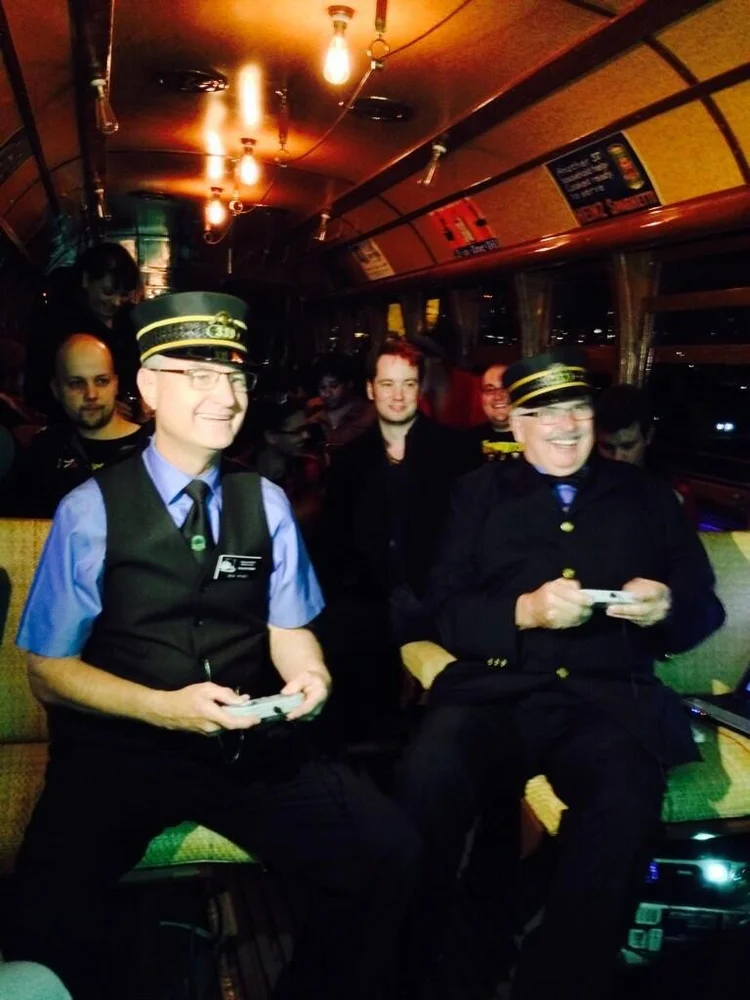 Two people in streetcar uniforms playing video games with controllers