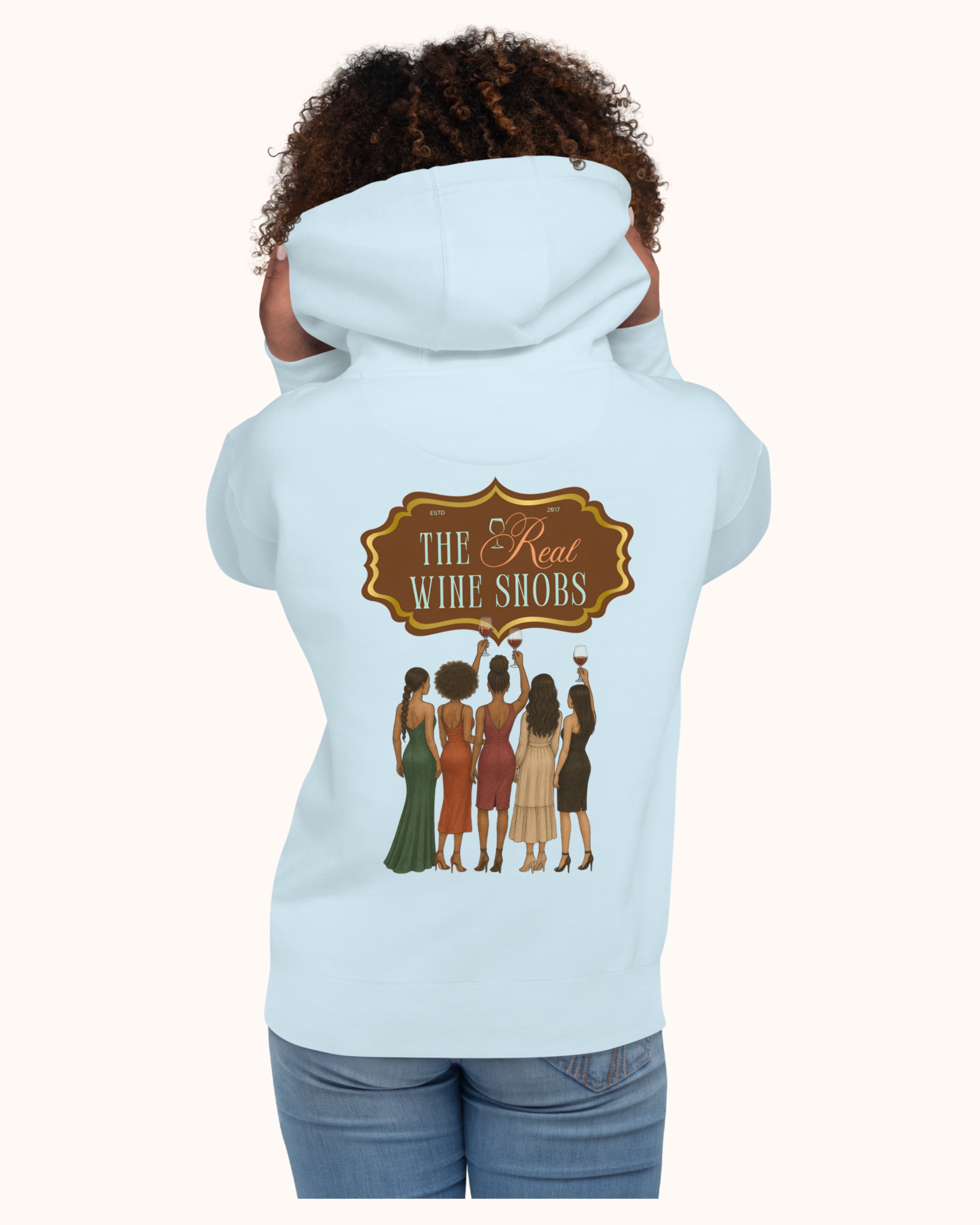 The Real Wine Snobs Snob Hoodie features women raising wine glasses beneath the brand crest. A fleece-lined hoodie designed for tastings, girls’ nights, and wine lovers with a little attitude.
