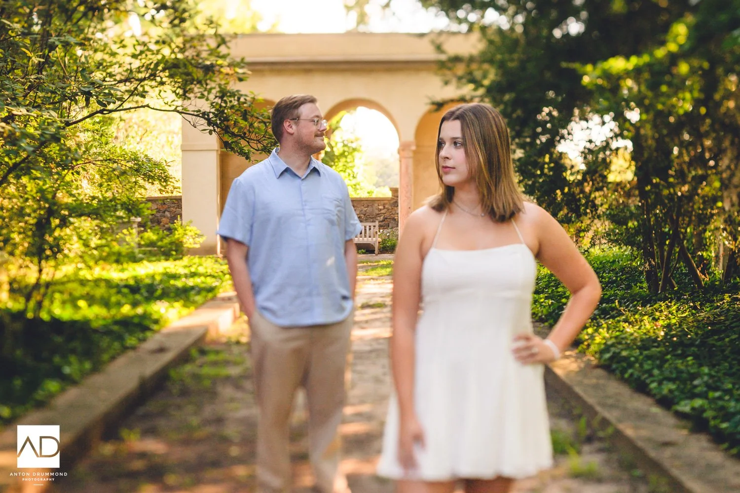 Bride to be in foreground as her partner gazes at her — New Castle County wedding photographer — Gibraltar loggia arch behind
