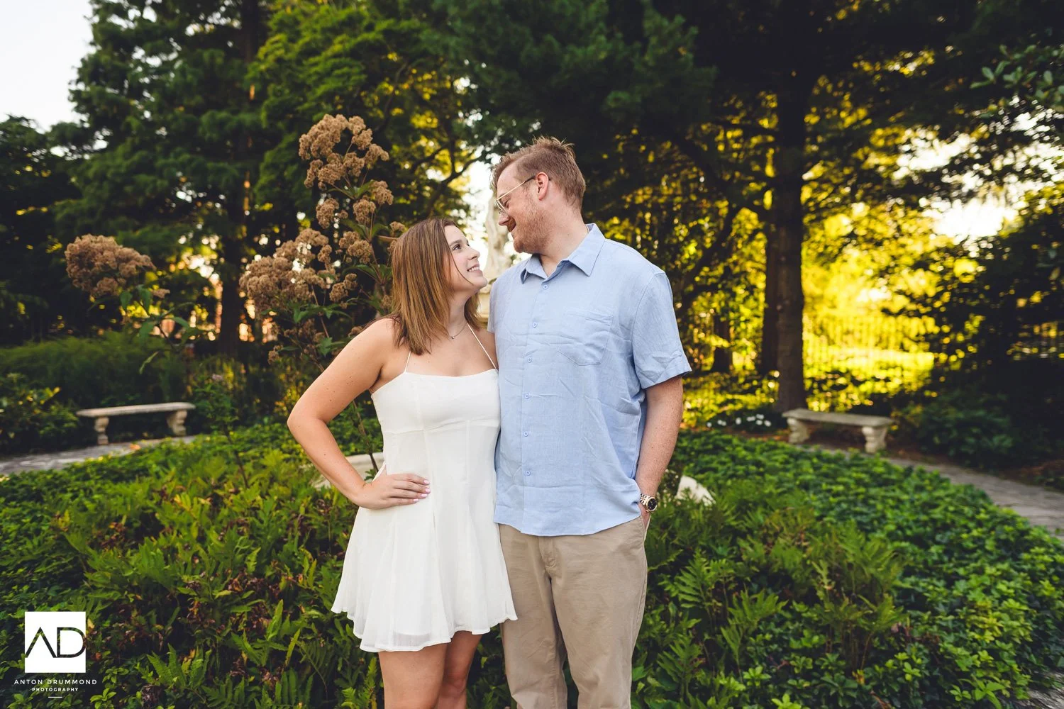 Wilmington DE engagement photographer captures couple laughing among dried sedum stalks and stone garden benches
