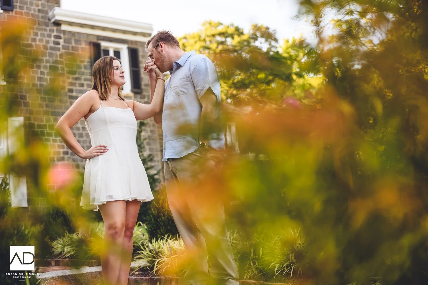 Wilmington DE engagement photographer captures hand kiss through colorful foliage, Gibraltar mansion beyond