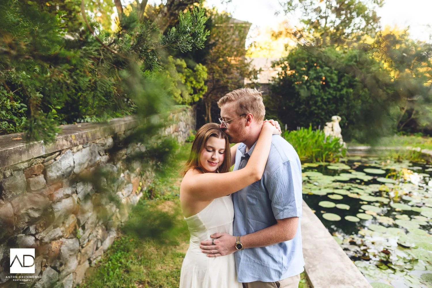 Anton Drummond captures a tender temple kiss by the lily pond at Marian Coffin Gardens engagement session