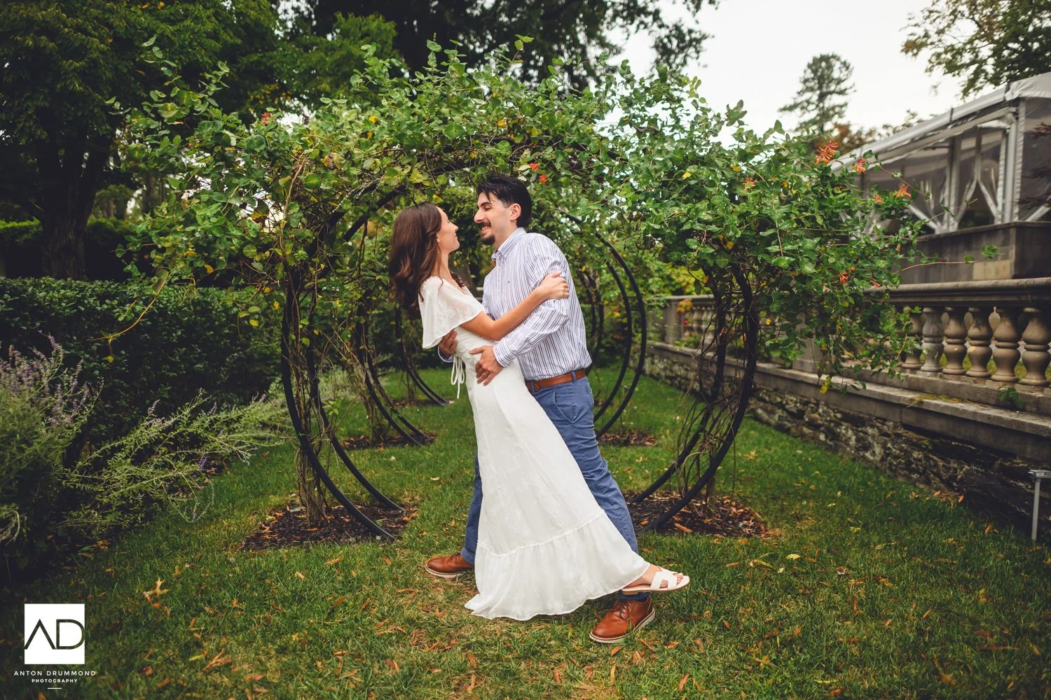 Emily and Joe mid-laugh in each other's arms inside the circular vine arbors — Curtis Arboretum engagement session