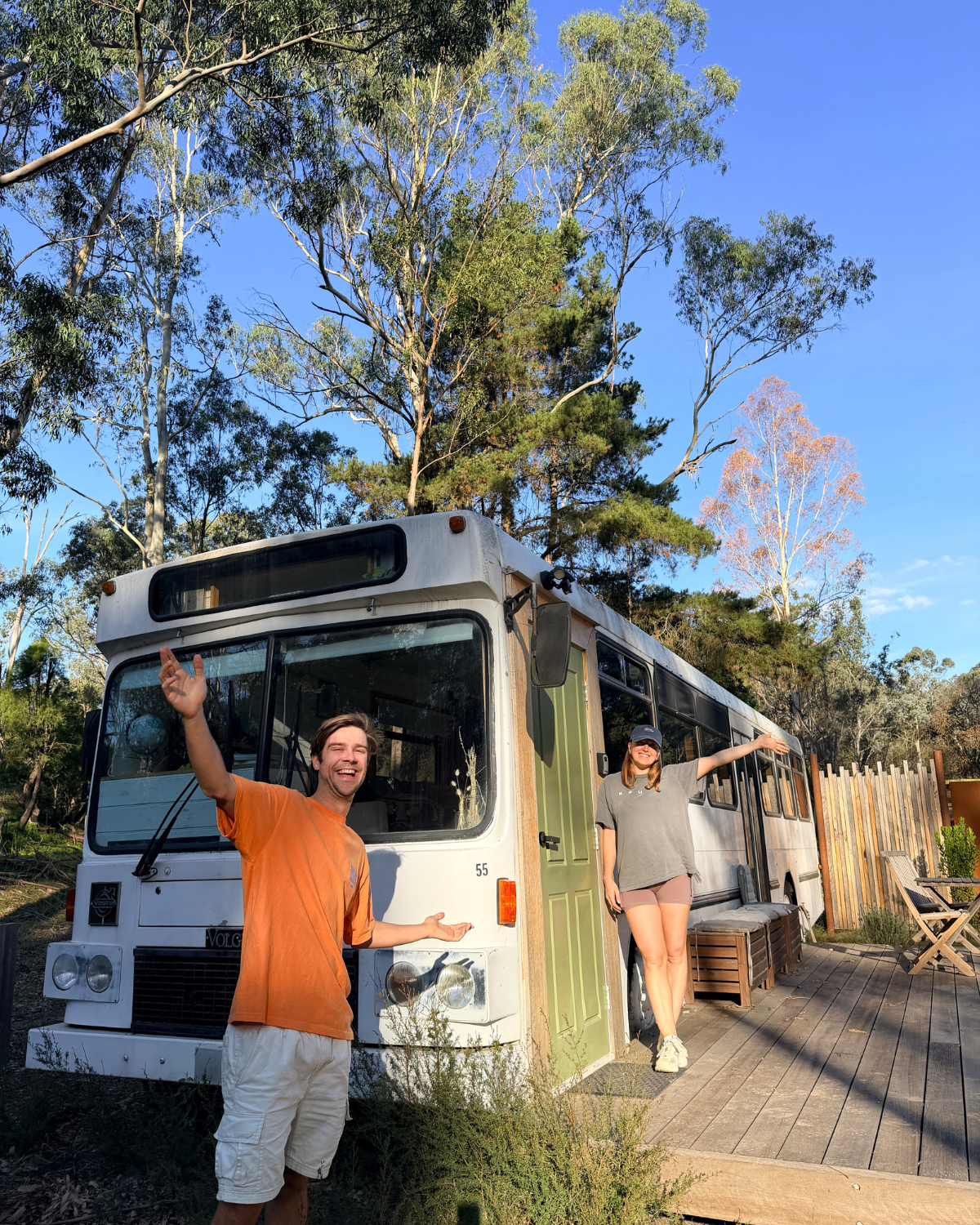 Hosts laughing and welcoming guests outside the Moss & Wheels converted bus on a sunny afternoon