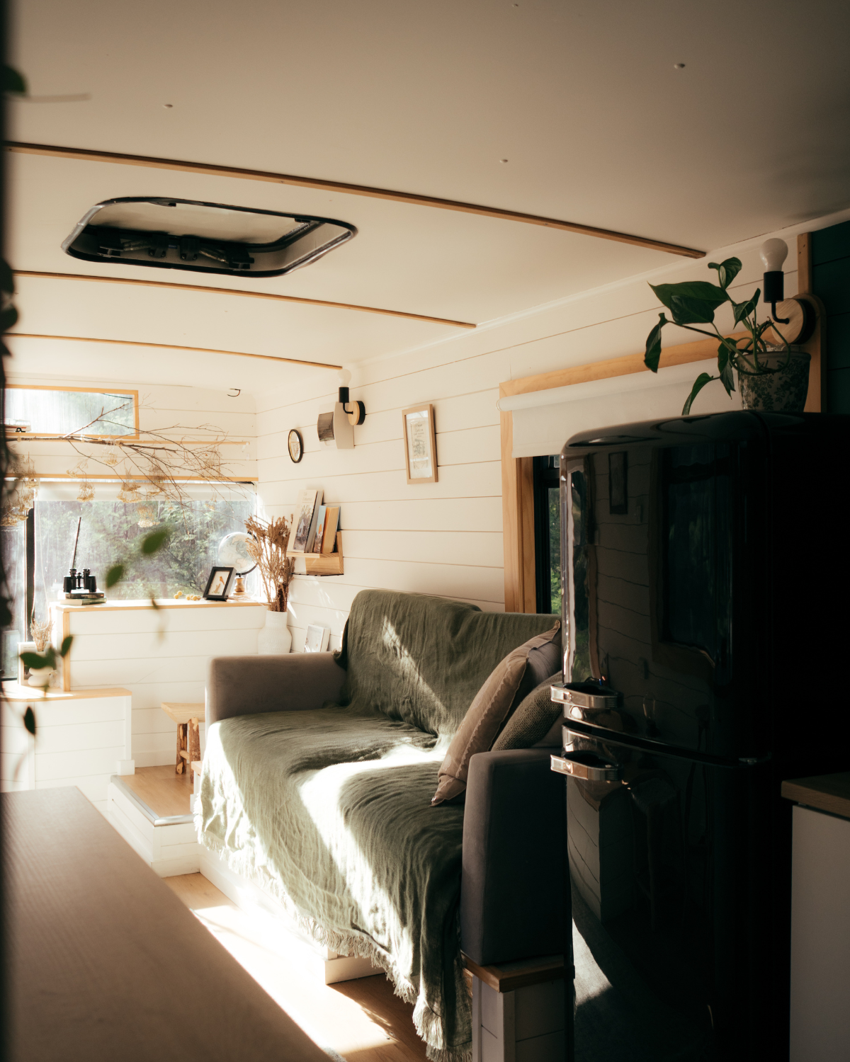 Cosy converted bus interior with timber walls, green linen throw and natural light, Cottles Bridge Victoria