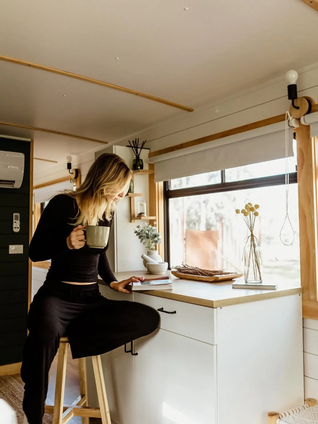 Woman enjoying a morning coffee at the bench inside the Moss and Wheels converted bus accommodation, Cottles Bridge