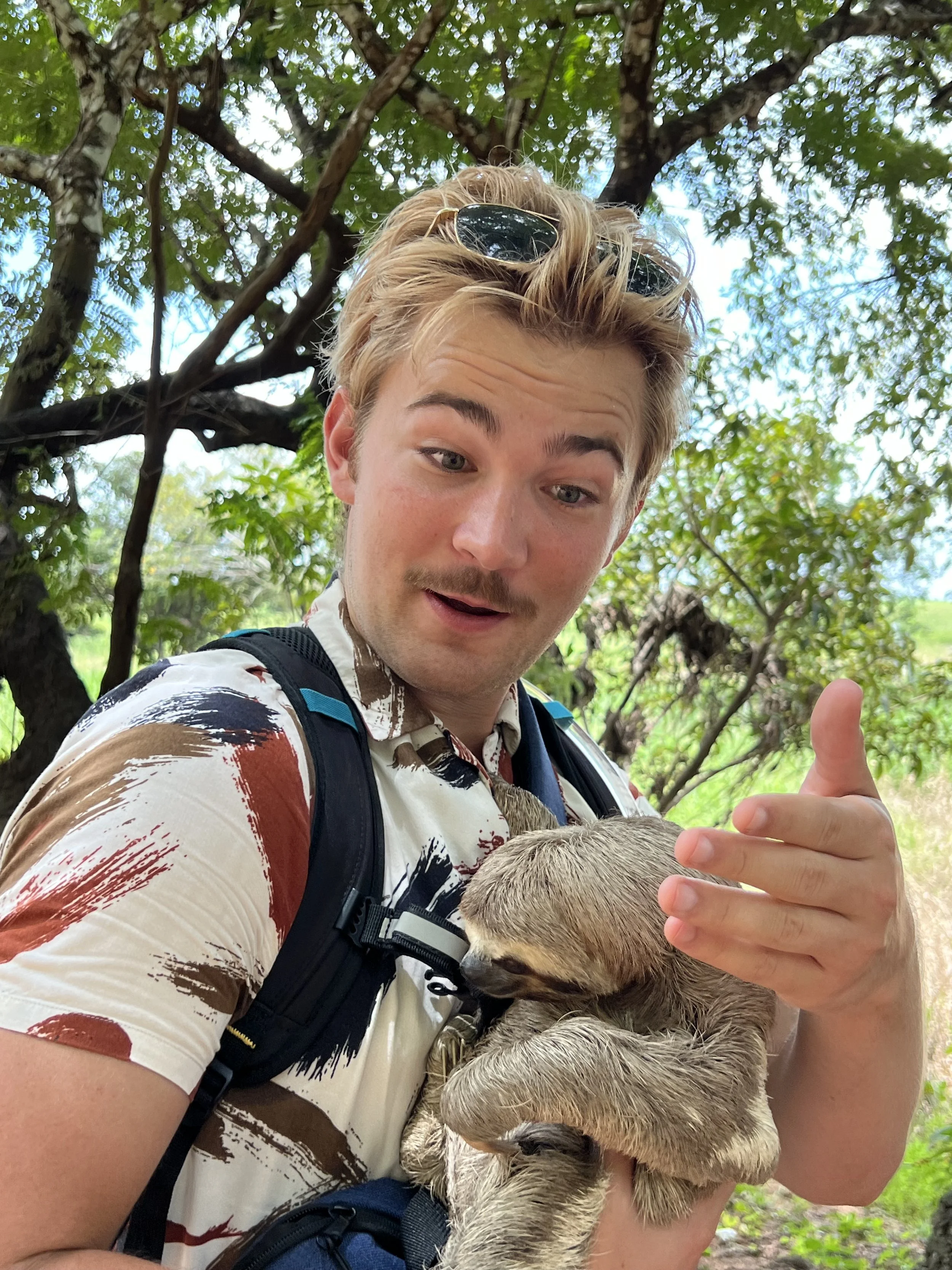 Giacomo with blond hair holding a sloth