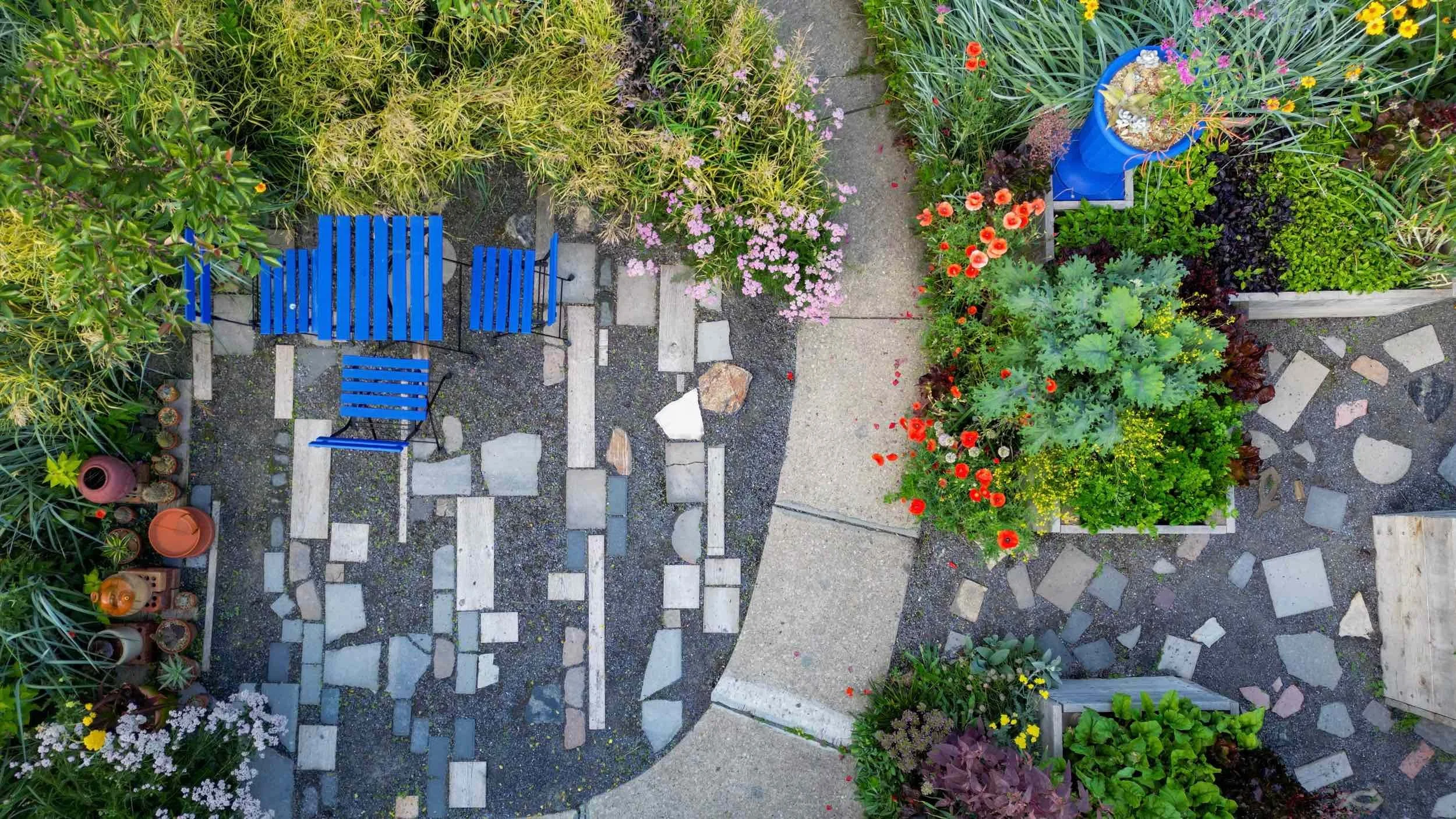 Drone view of Garden Living with blue patio furniture, paths and planting beds wrapped in flowers