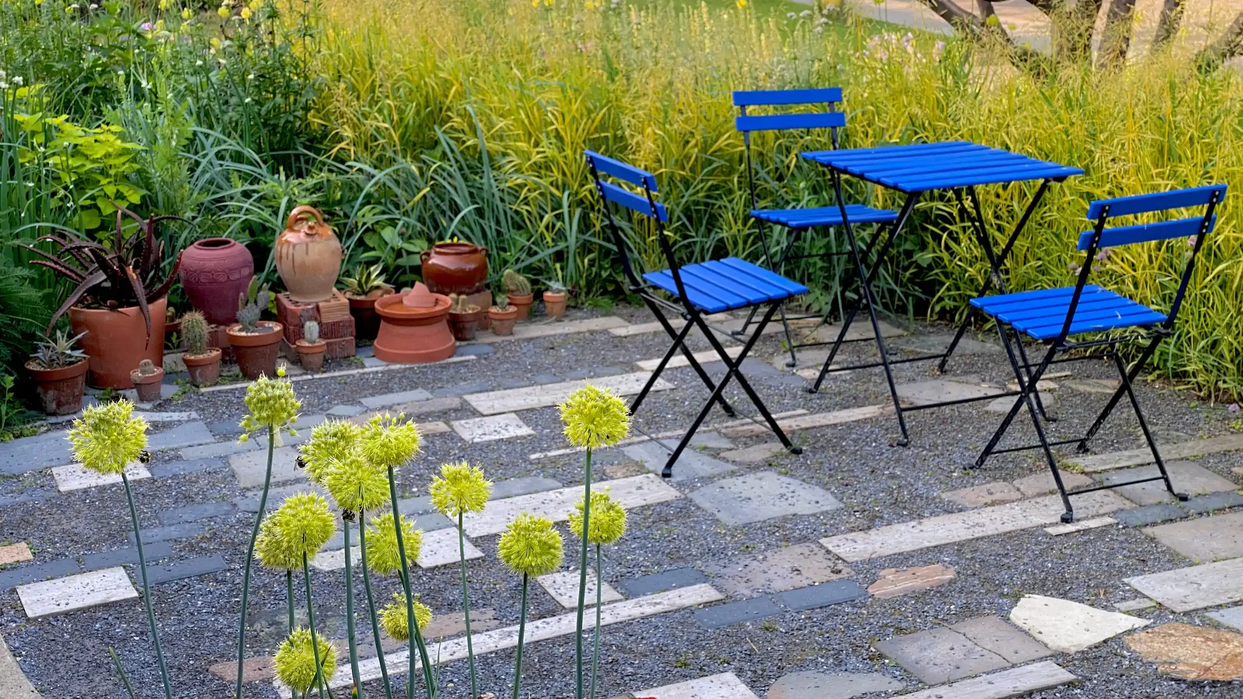 Patio table and chairs beside lush meadow planting creating an inviting space for planting design consultation in Edmonton