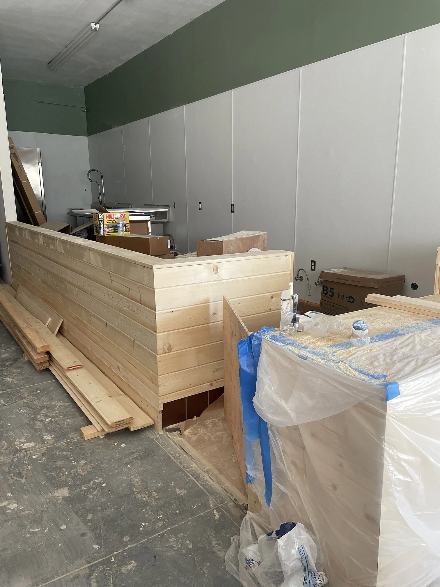 Construction site with wooden panels, boxes, and construction supplies in a partially finished room.