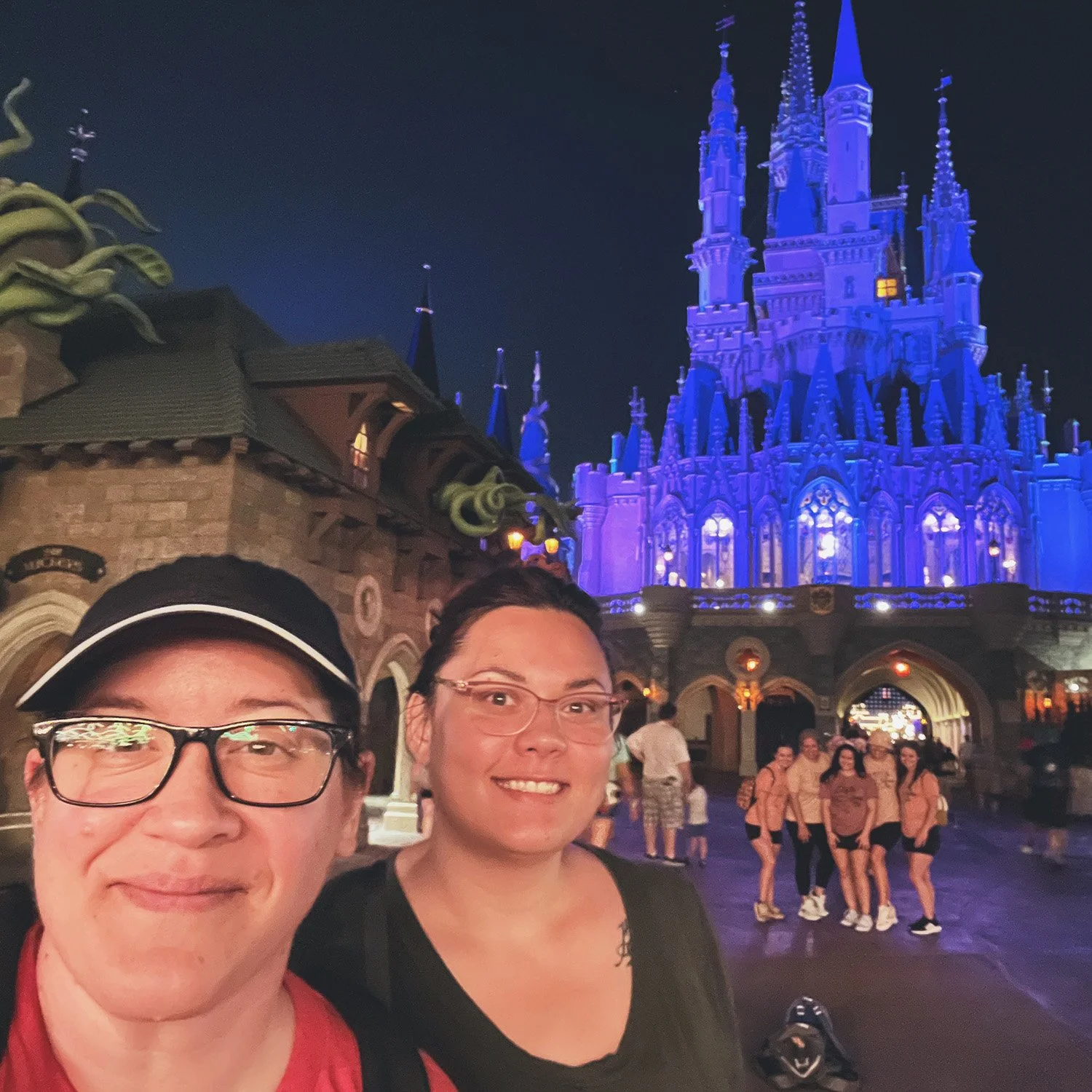Lori and BFF Erica at the Disney World castle at night on the Fantasy land side