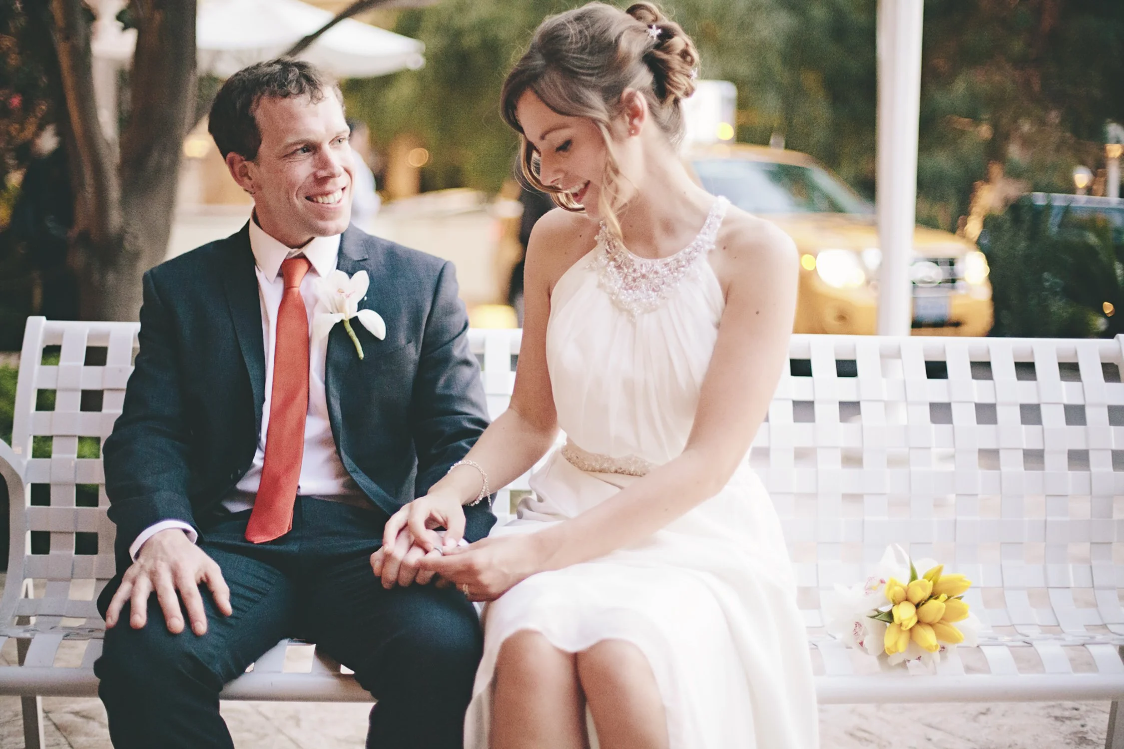 a newly married couple sitting on a bench at the Wynn valet. They are smiling at candidly talking about their elopement in Las Vegas.