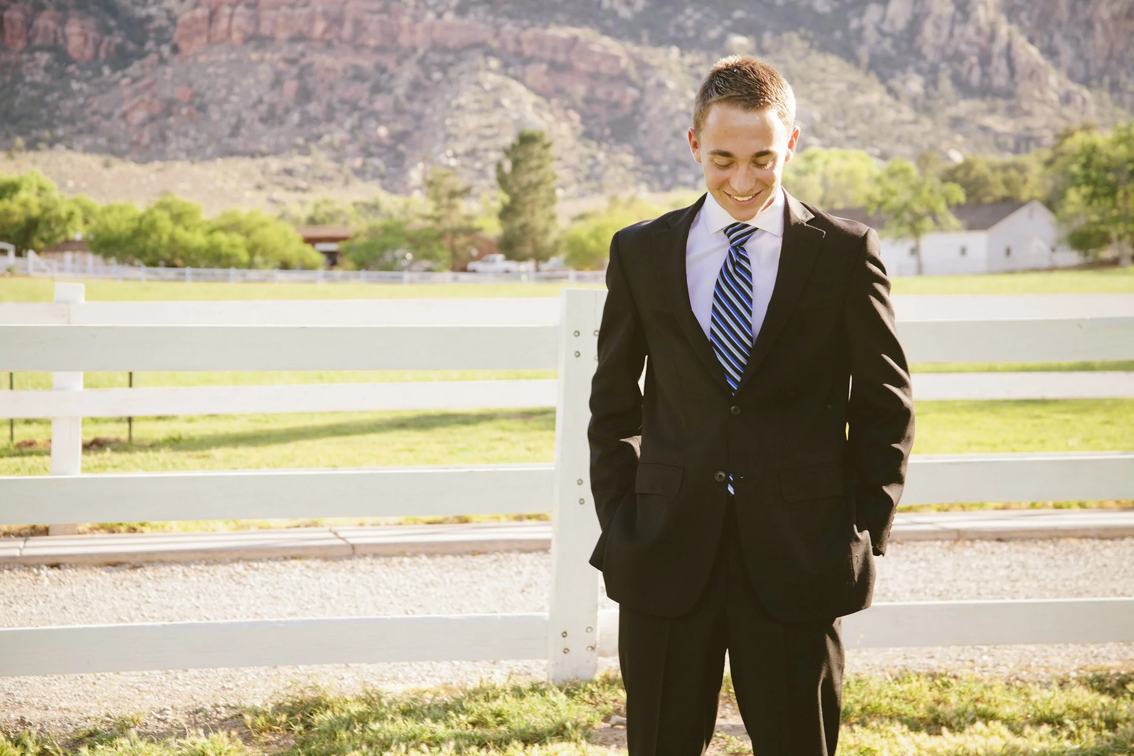 a young man in a suit and tie is smiling but looking towards the ground, standing in a state park Spring Mountain Ranch, this is anticipation of going on a mission for the LDS church