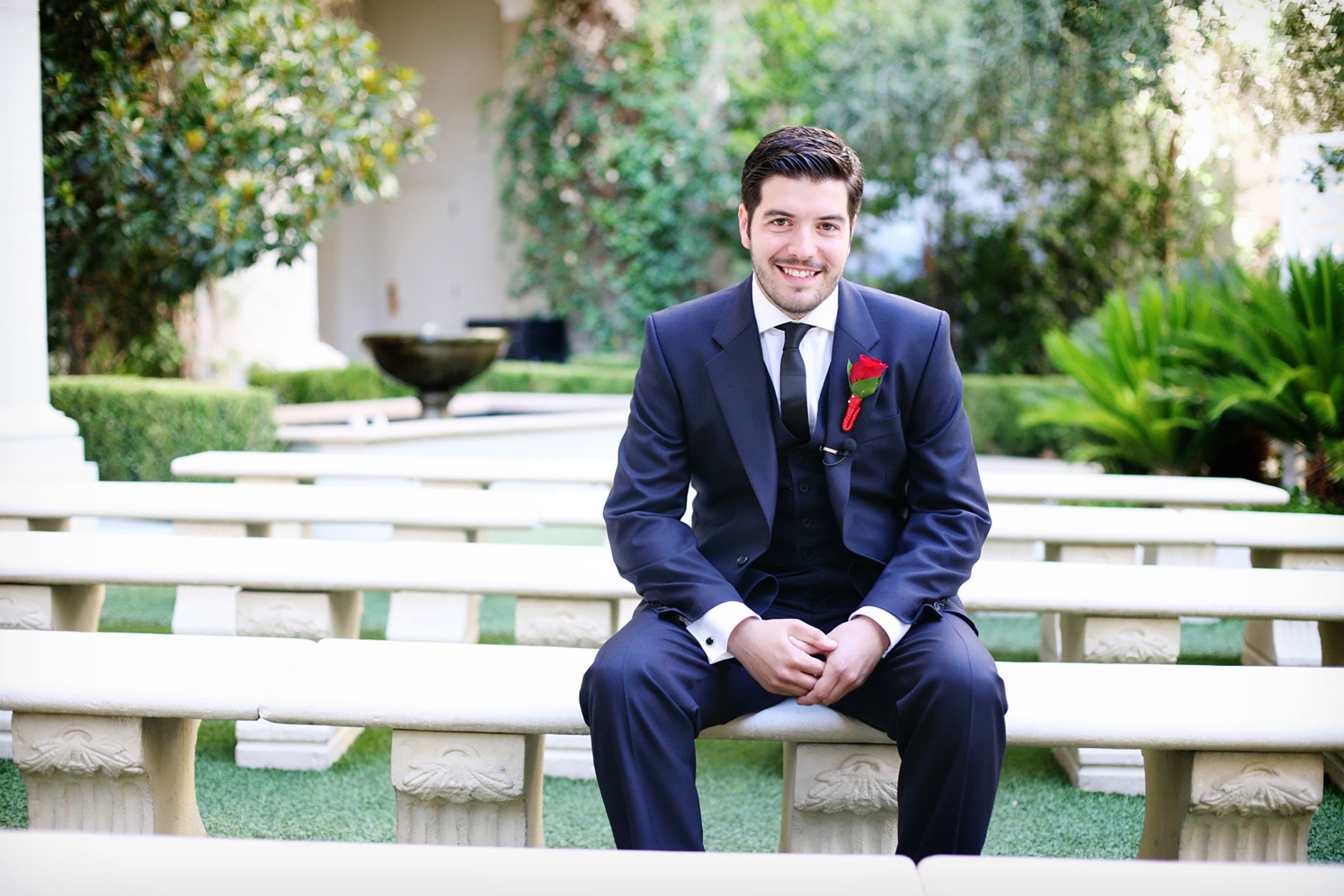 a groom is smiling at the camera sitting among benches before his elopement wedding.