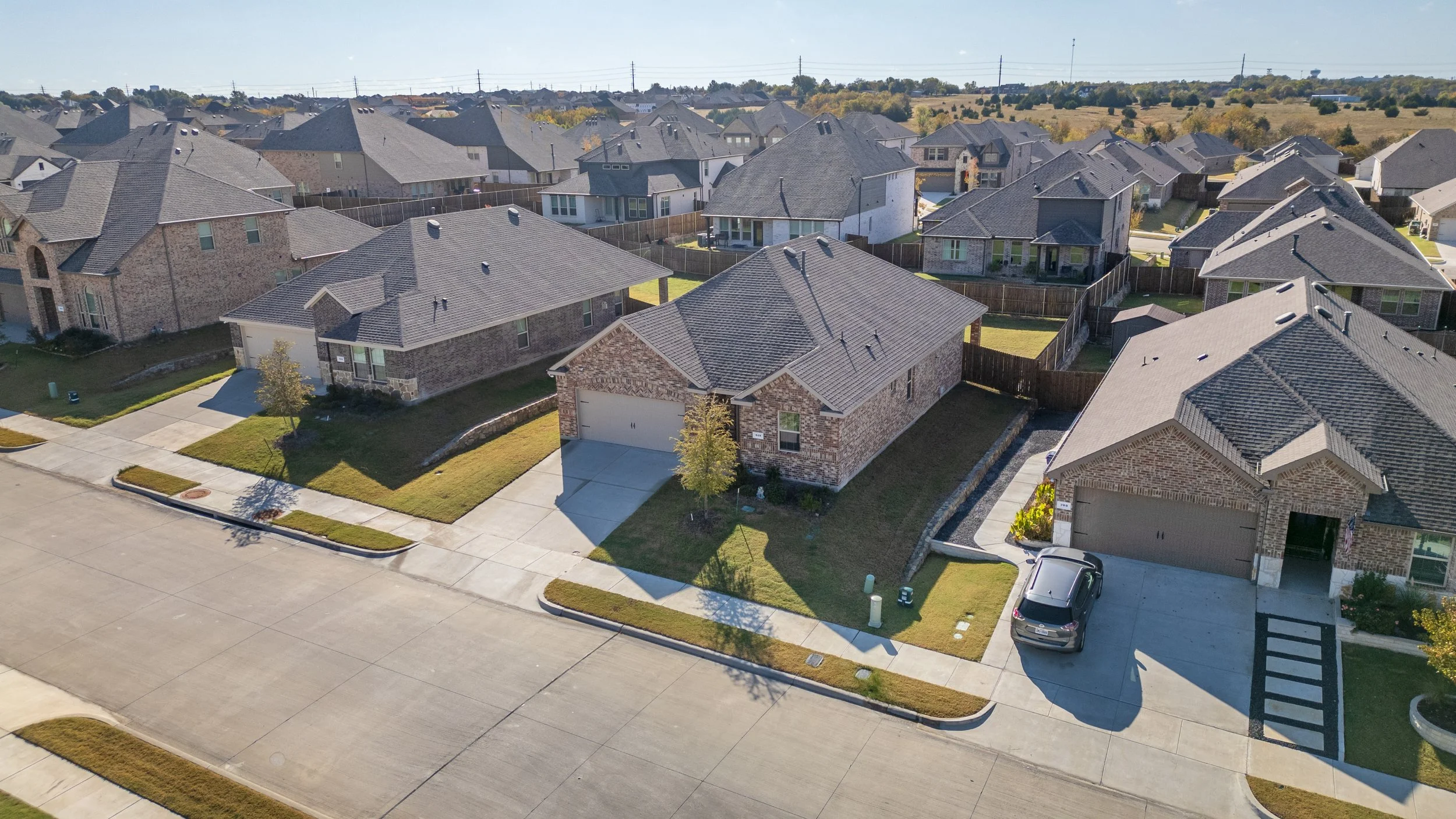Aerial view of a suburban neighborhood with single-family homes, driveways, and sidewalks.