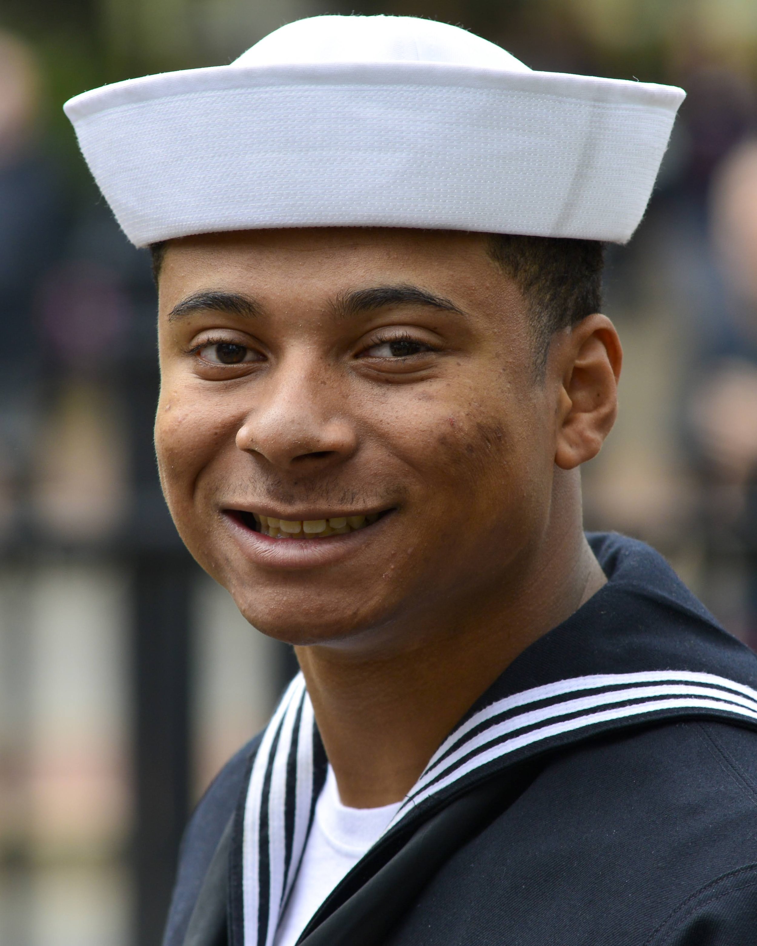 Justin Parker wearing a U.S. Navy sailor uniform and white hat, smiling at the camera.