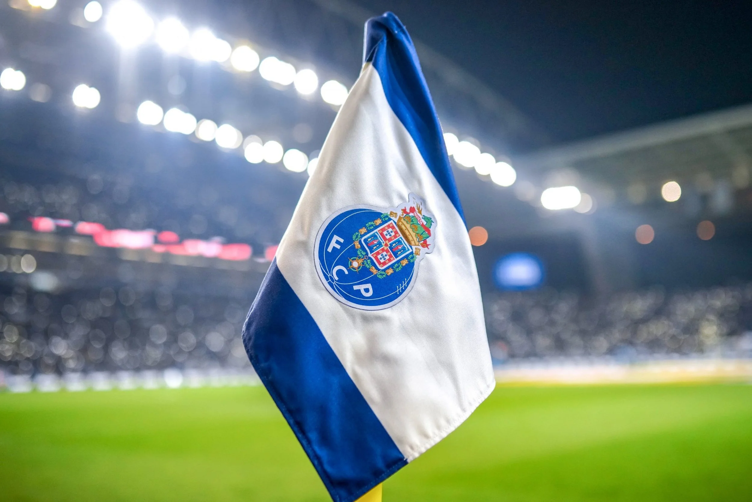 A F.C. Porto flag on a stadium field with bright lights and blurred crowd in the background.