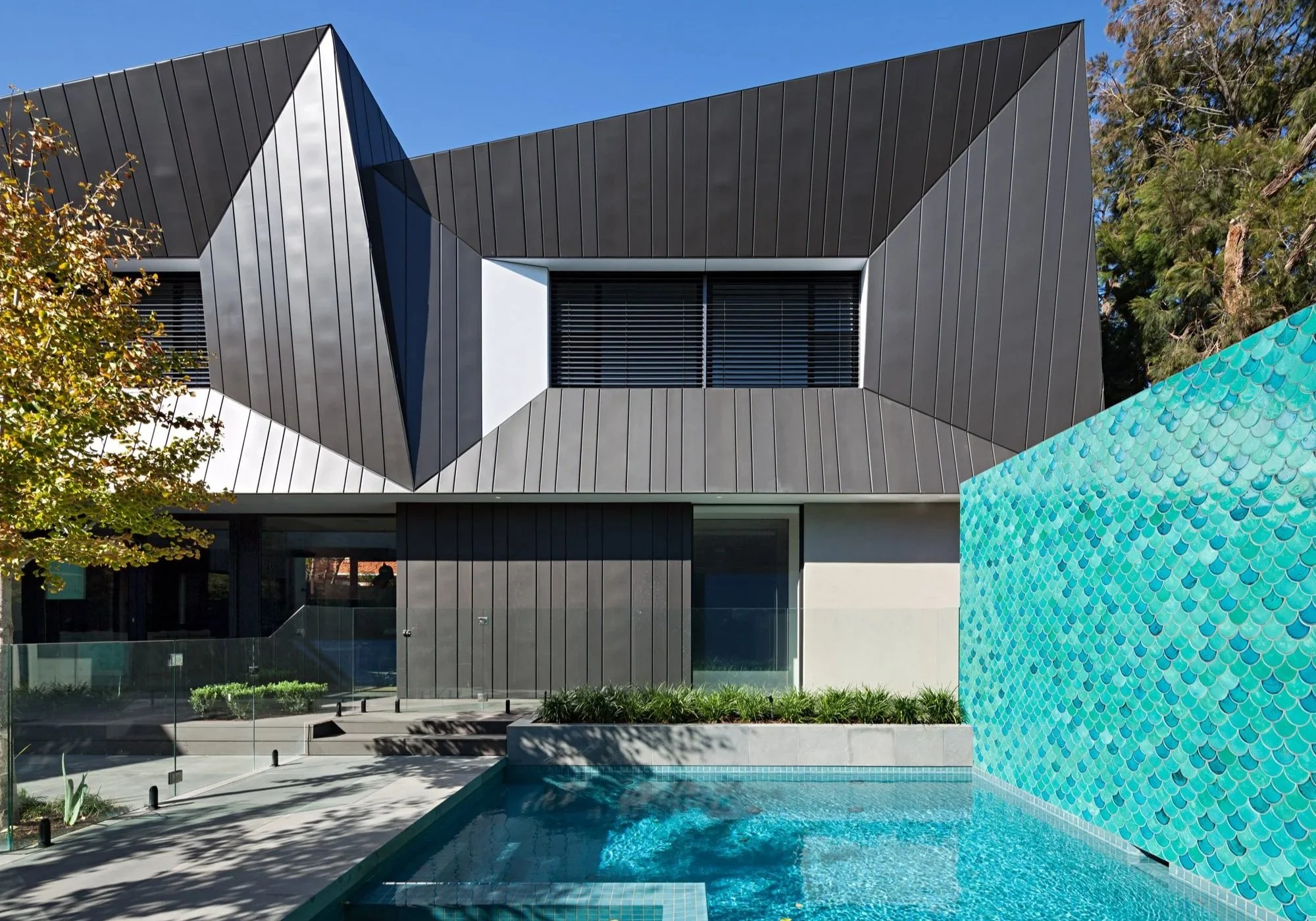 Contemporary residence with non-standard metal cladding and complex facade interfaces beside a swimming pool
