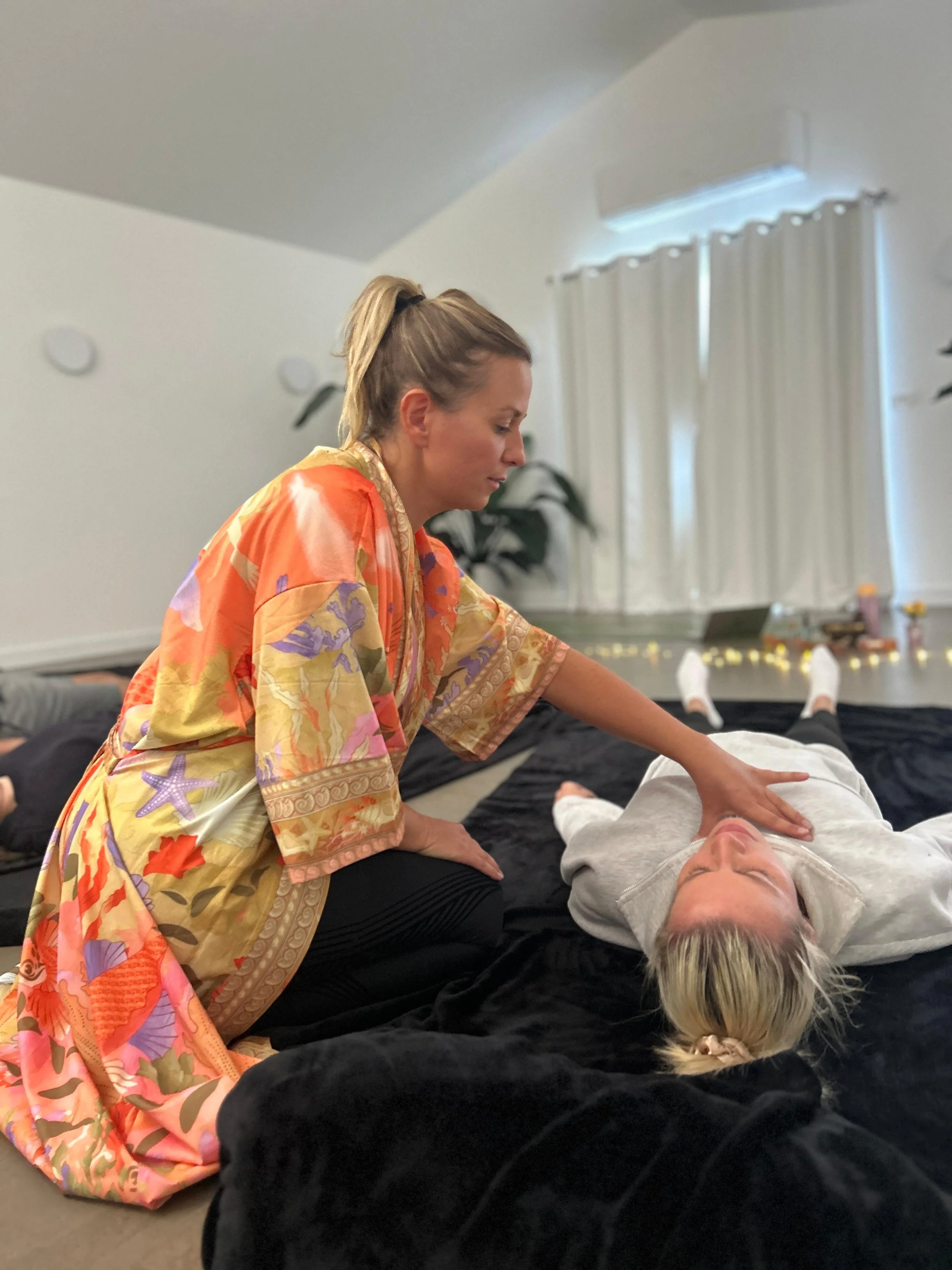 A woman performing CPR on a person lying on a black blanket in a living room.
