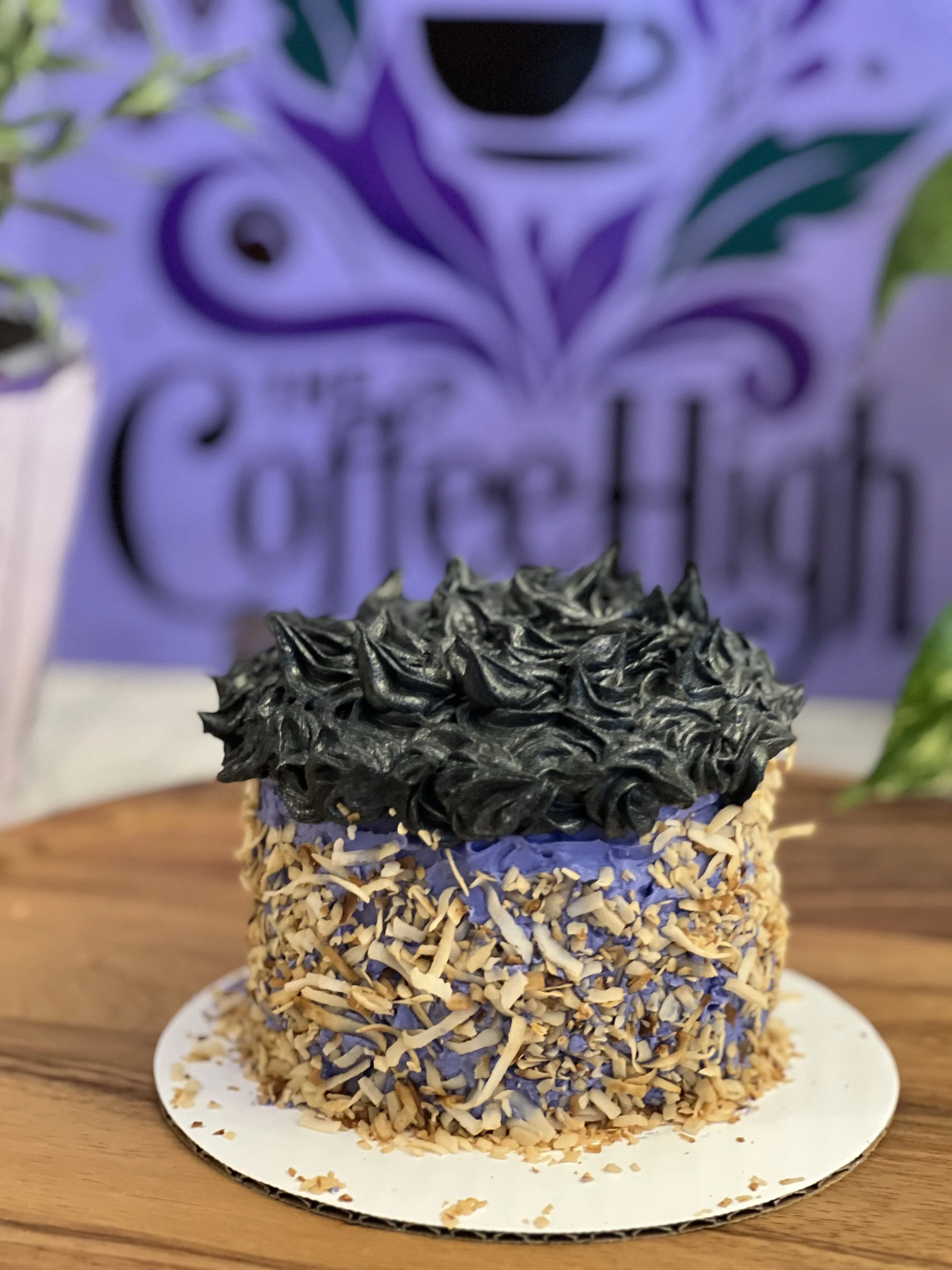 Purple and black frosting piped around the cake with toasted coconut flakes